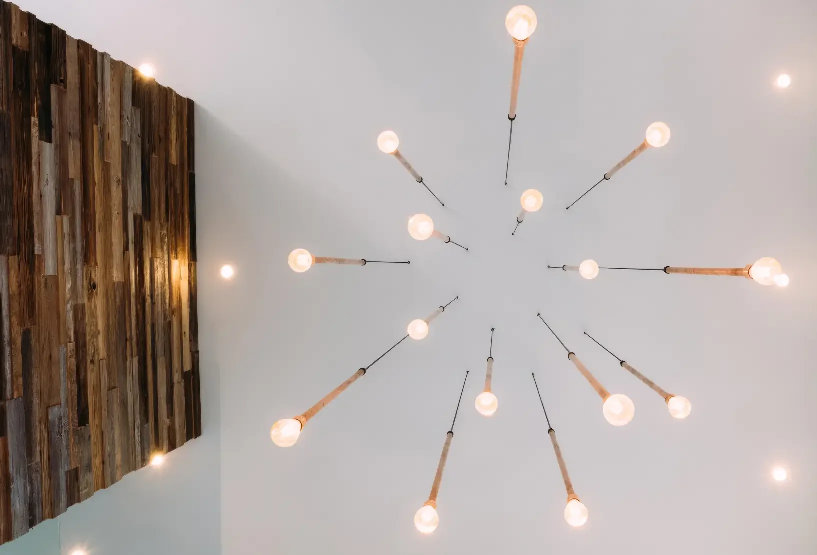 Bespoke copper pipe light installation viewed from below, with exposed bulbs arranged across the ceiling.