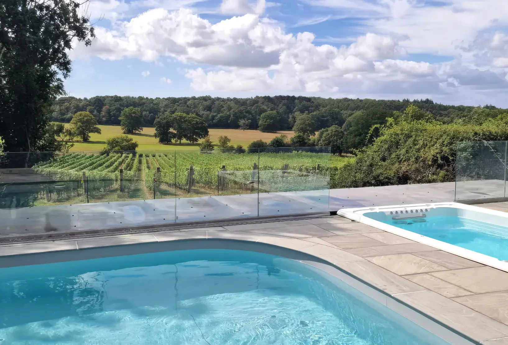 Outdoor swimming pool and hot tub overlooking the Hampshire countryside and Quob Park vineyards.
