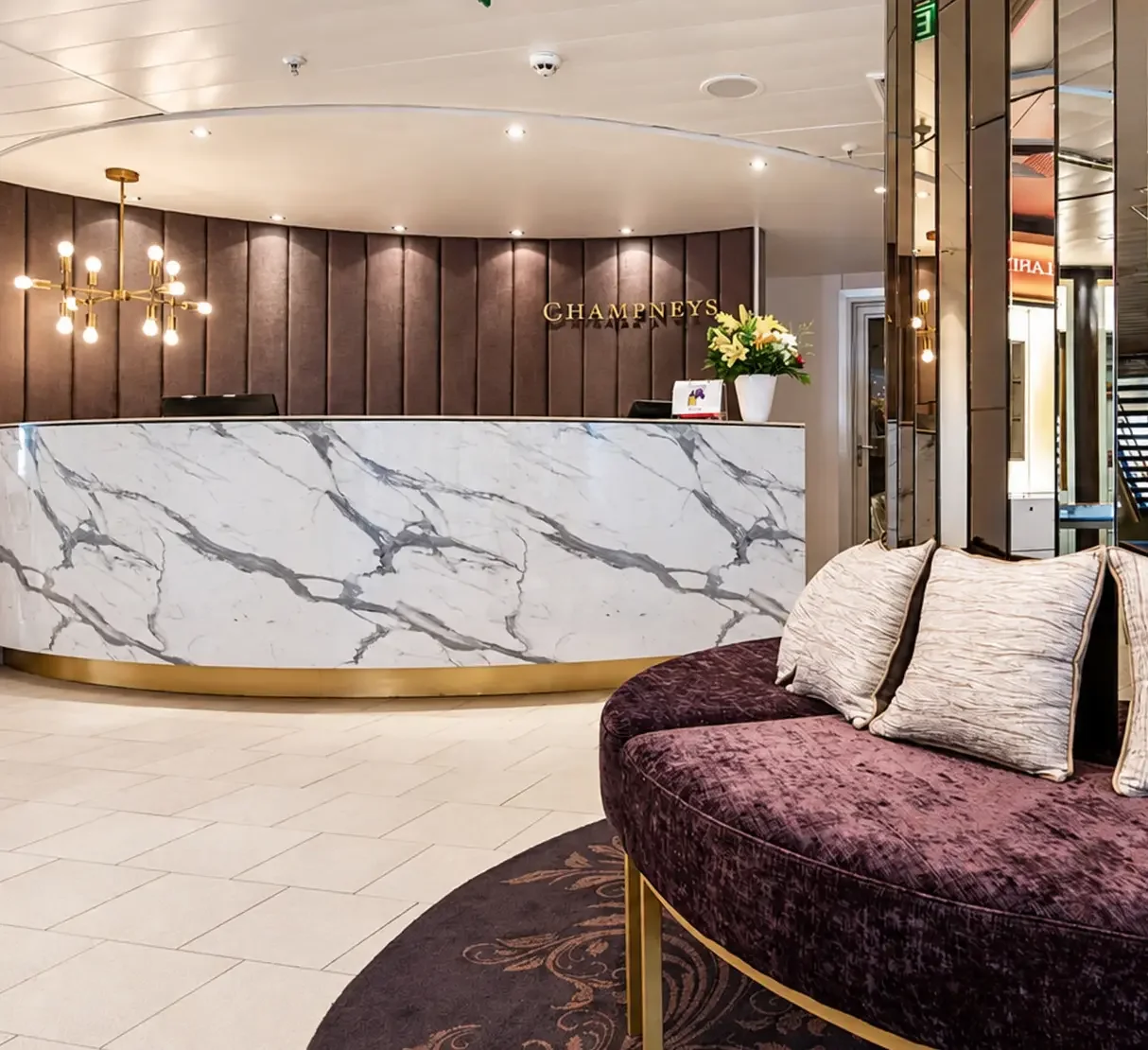 Champneys spa reception and waiting area with bespoke reception desk and decorative feature backdrop.