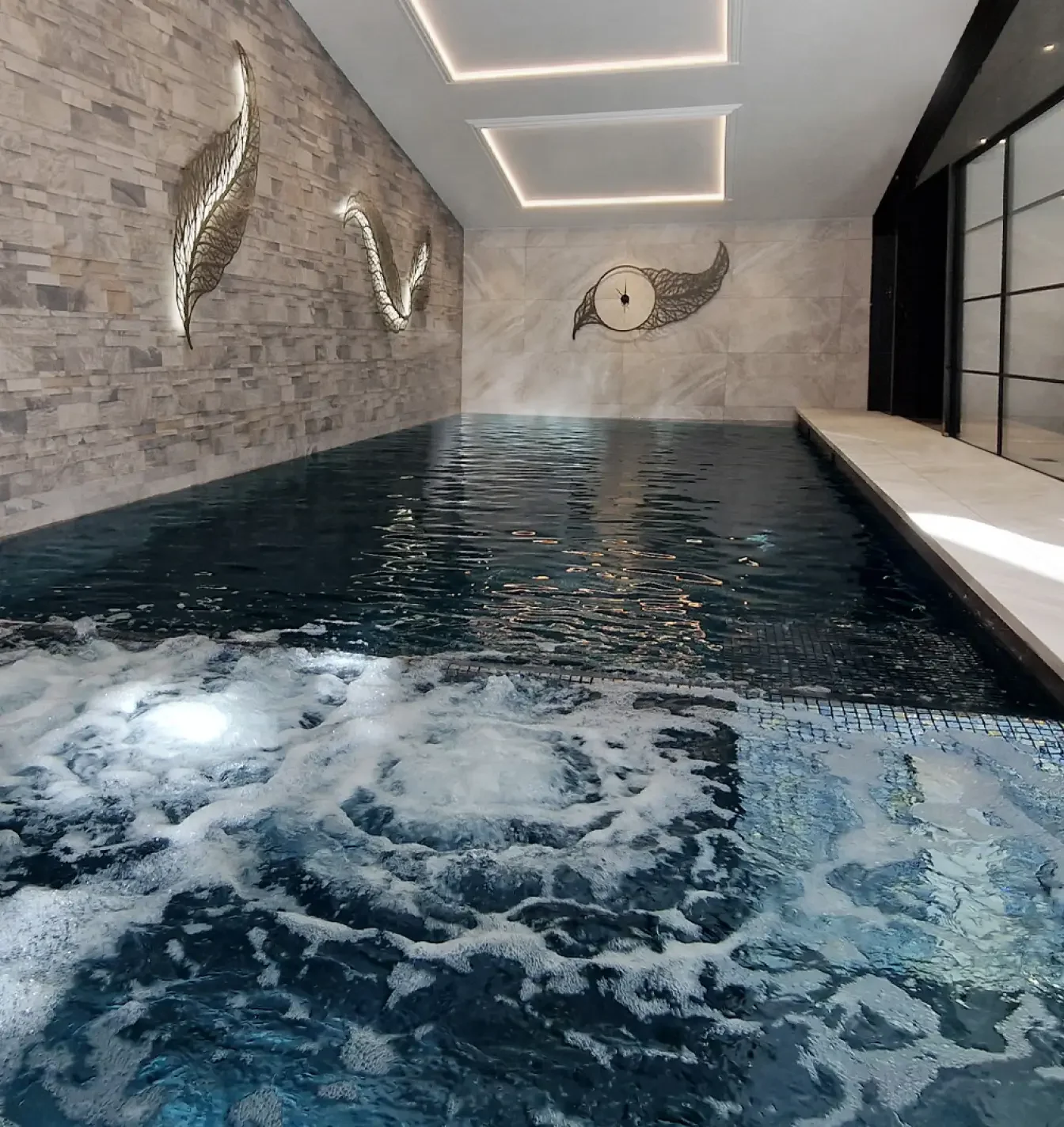 Private Residential pool with bespoke artwork on walls and hydrotherapy pool bubbling in the foreground