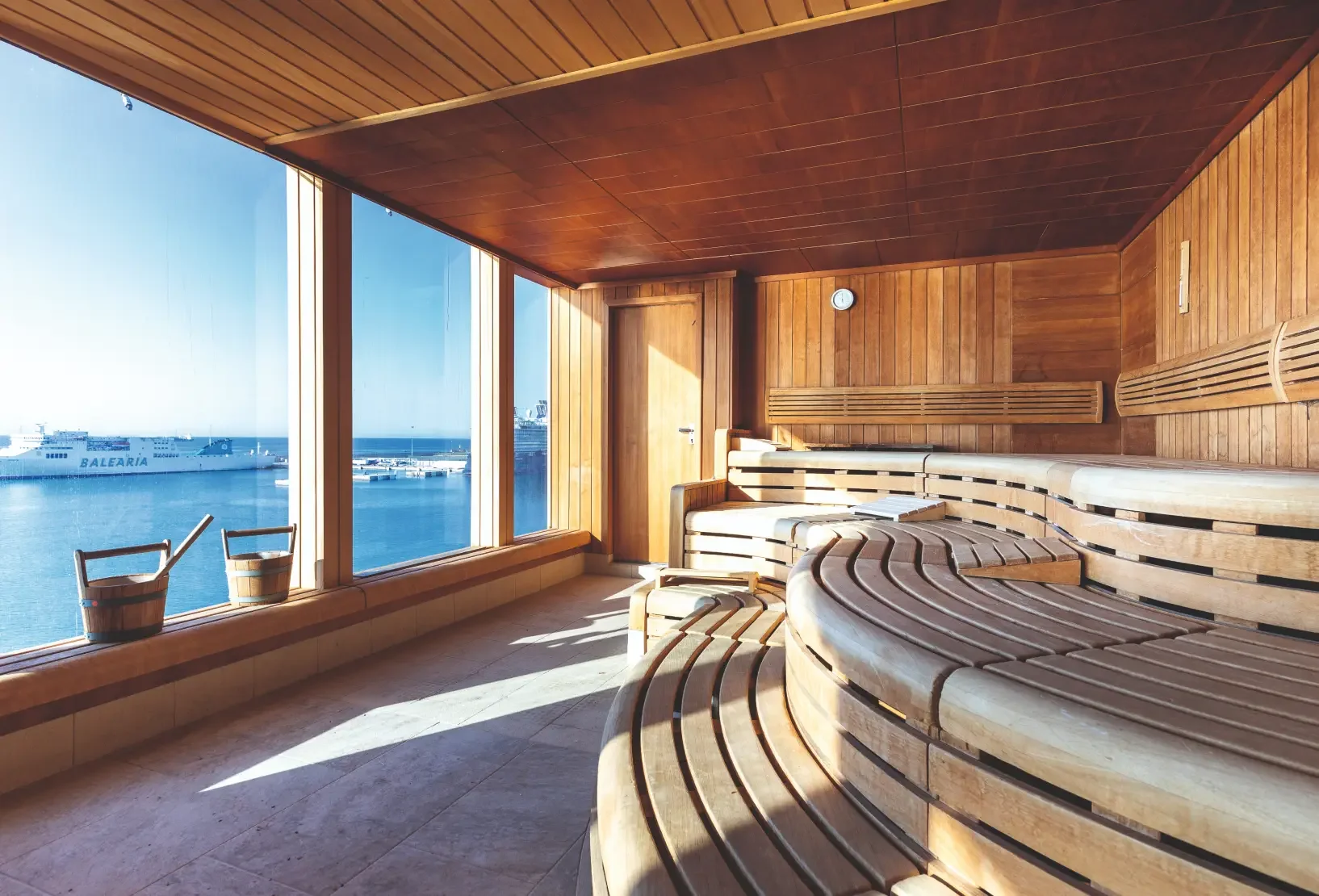 Timber sauna with curved tiered seating and panoramic views across the sea.