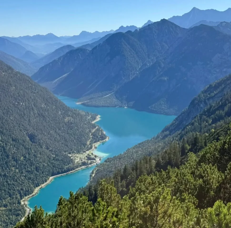 Türkisblauer Plansee umgeben von bewaldeten Bergen in Tirol.