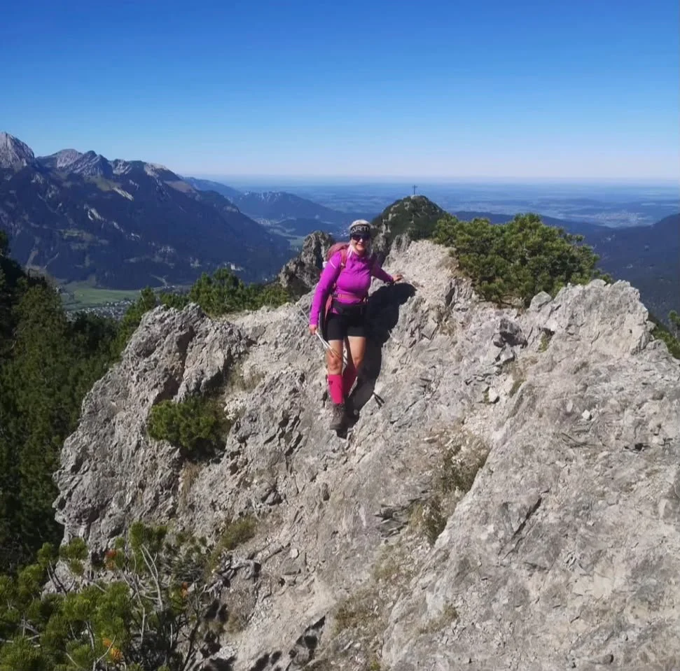 Wanderin auf dem felsigen Weg zur Tauernspitze mit dem Zunterkopf im Hintergrund.