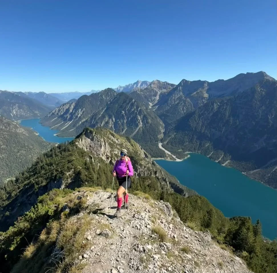 Wanderin auf dem felsigen Weg zur Tauernspitze mit Panoramablick auf den Plansee und den Heiterwanger See in Tirol.