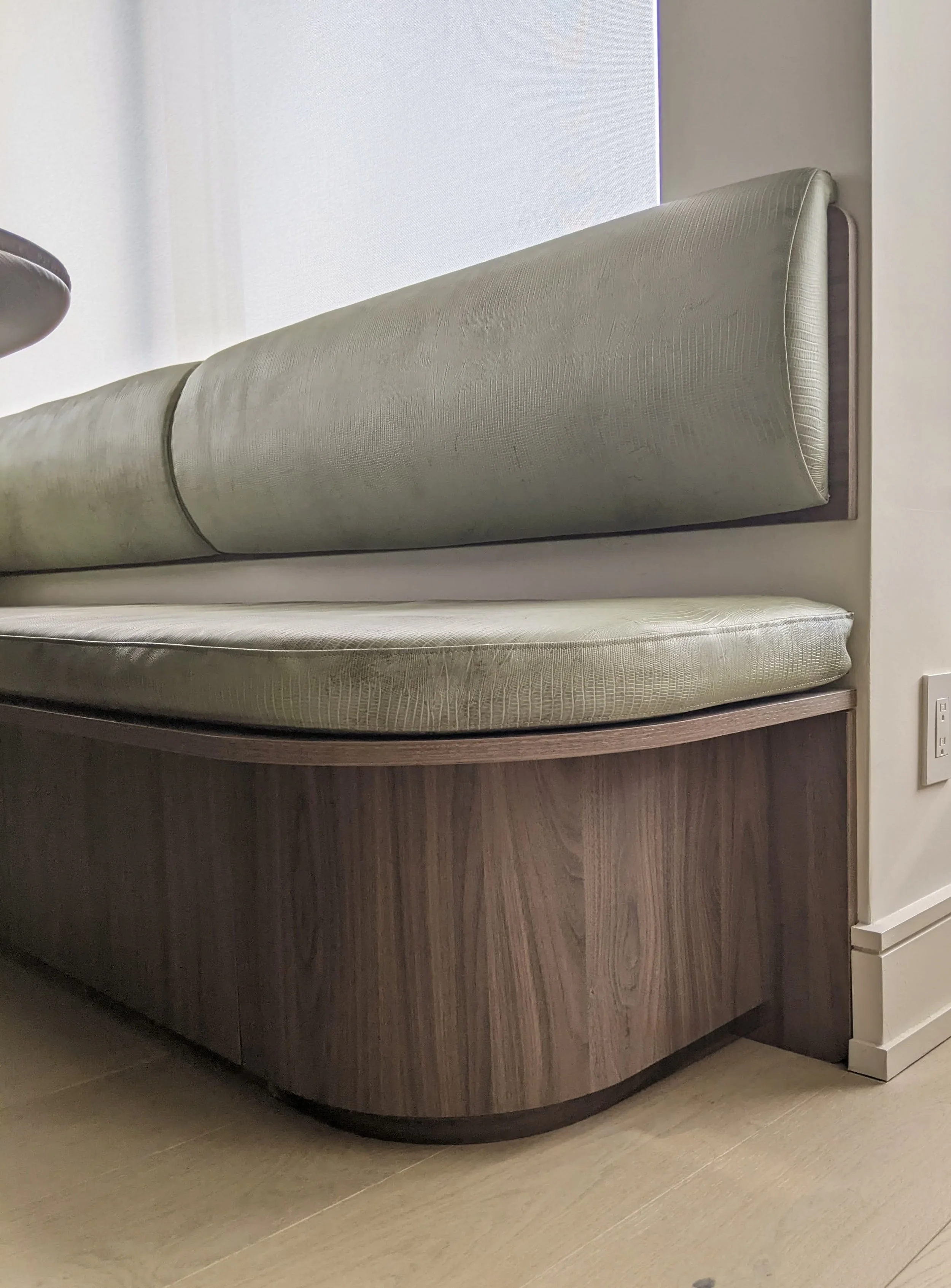We used the same walnut effect laminate on the banquet to match the bar and media console. The upholstered cushions and backrest are covered in a green textured leather. 