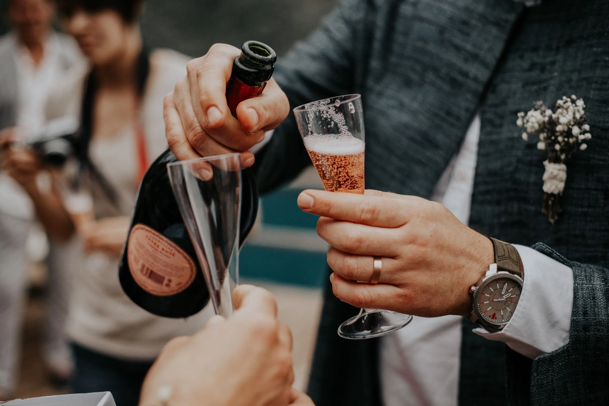 Person pouring pink sparkling wine into a glass at a social gathering