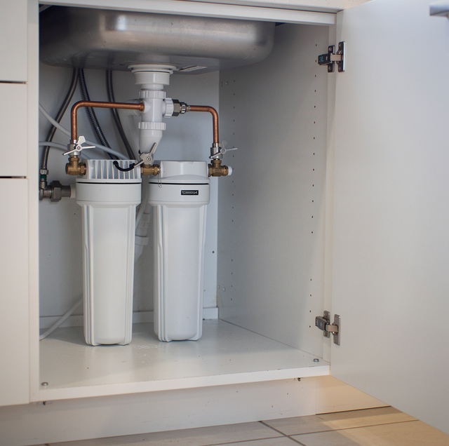 Plumber installing under-sink water filtration system