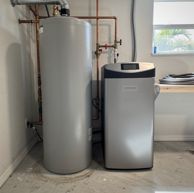 technician installing high-efficiency water softener beside residential plumbing