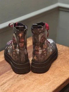 Pair of black combat boots with red accents on a wooden surface.
