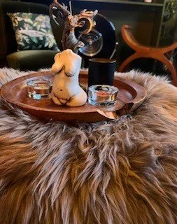 Decorative tray with a small figurine of a seated cat, two shot glasses, and a car key, placed on a furry surface.