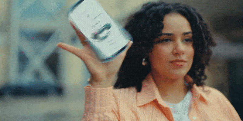 A woman with curly hair holding a can of food, looking confident.