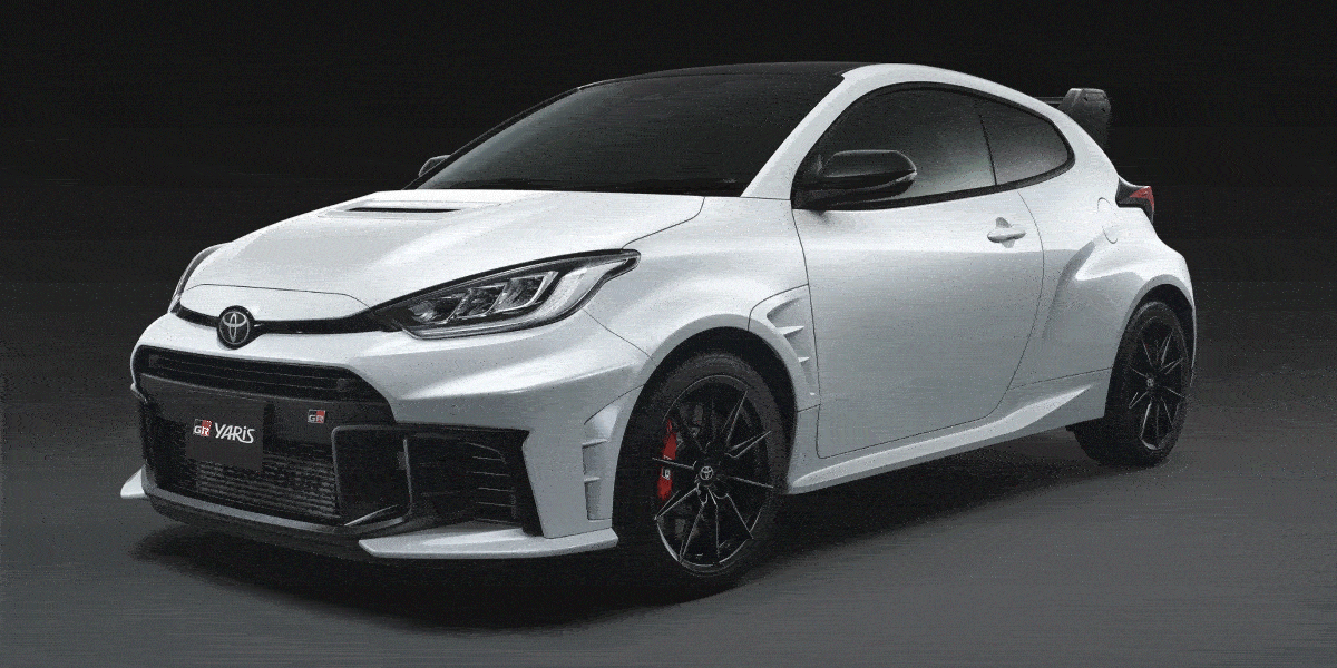 A white Toyota GR Yaris with black wheels and red brake calipers, showcased against a dark background.