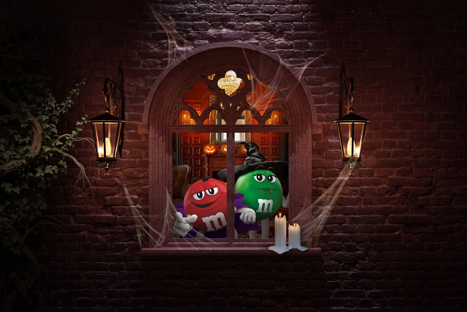 A spooky Halloween scene with a brick wall, cobwebs, candles, and a window opening to a decorated room. Inside the window, there are animated red and green M&M characters dressed in costumes, with Halloween pumpkins and a witch hat visible in the bac