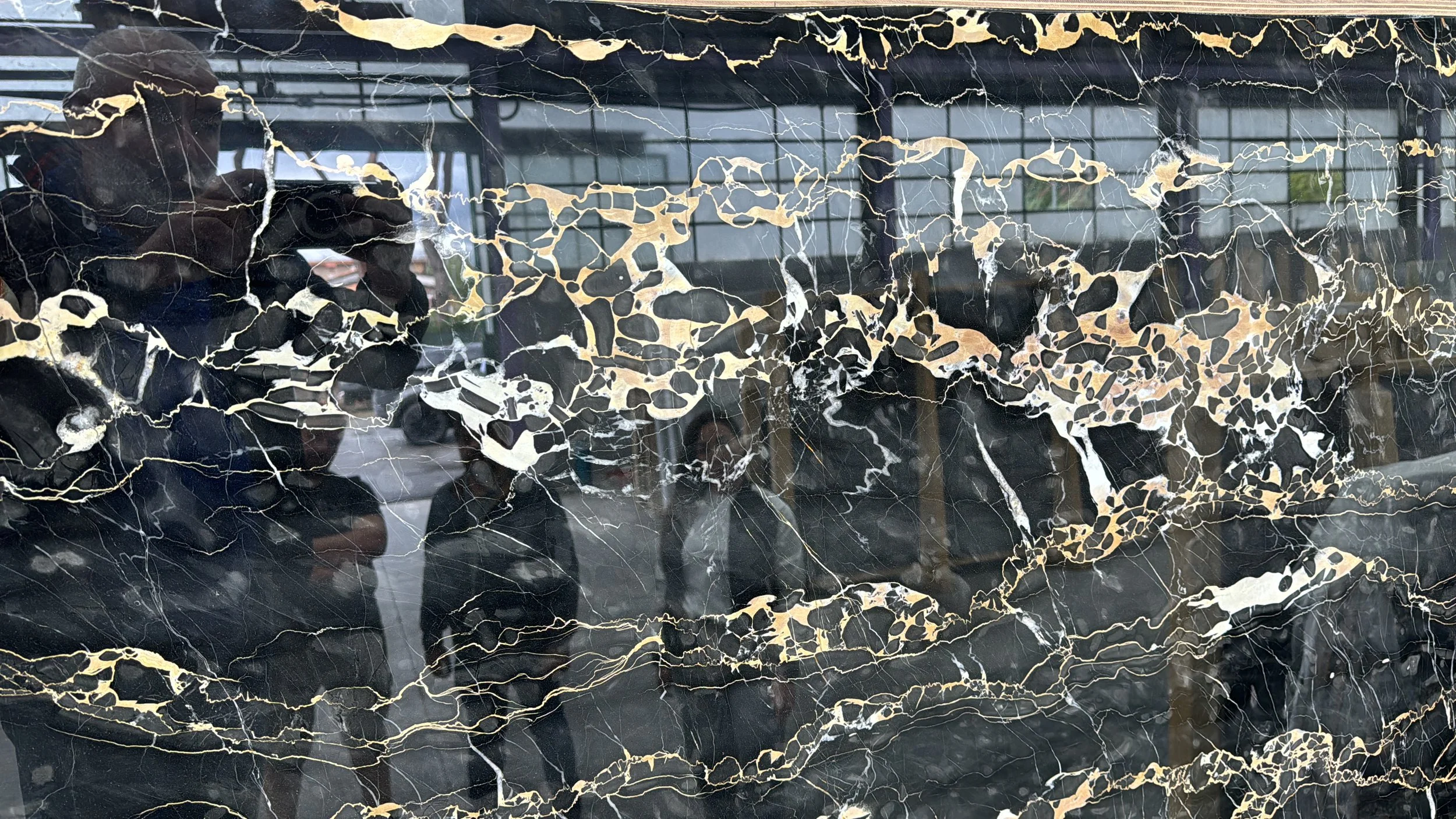 Close-up of black marble with gold and white veining and reflections.