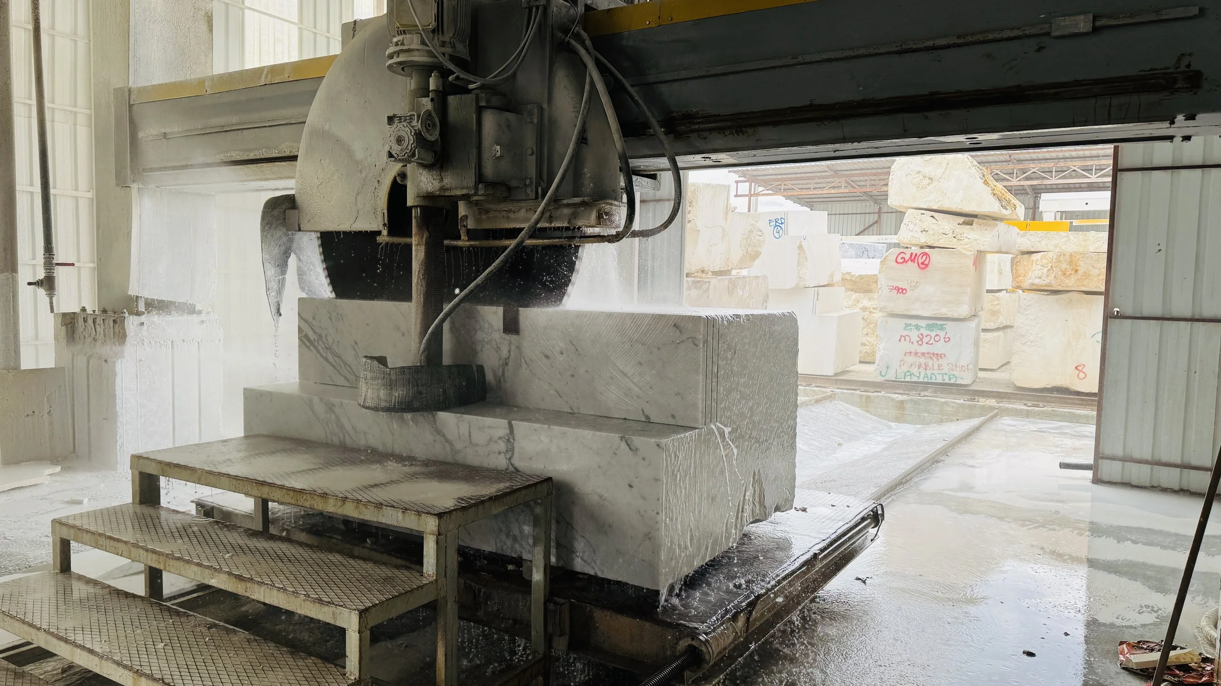 CNC machine cutting a large marble block at G STONE's production facility.