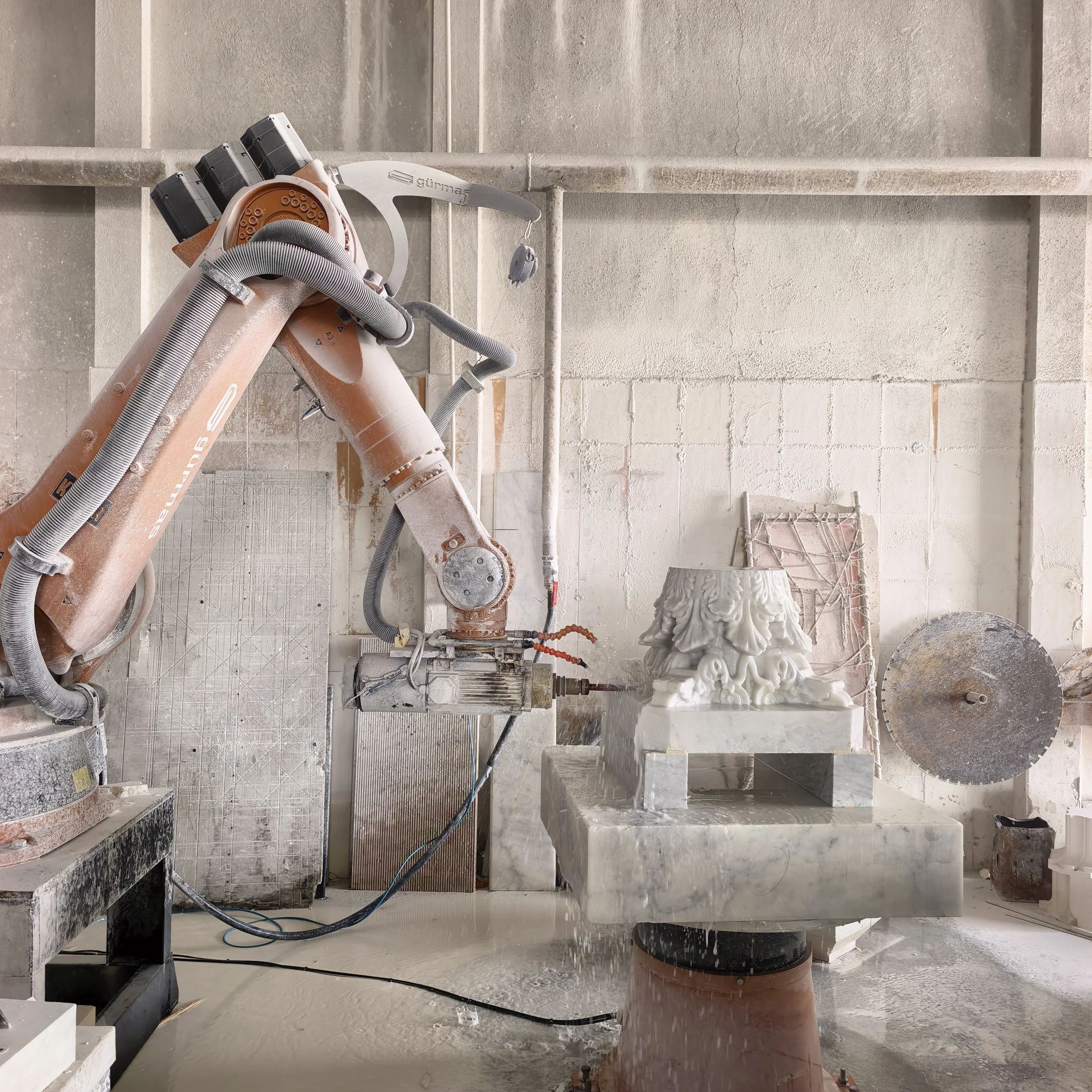 Robotic CNC arm shaping a stone block at G STONE's production facility.