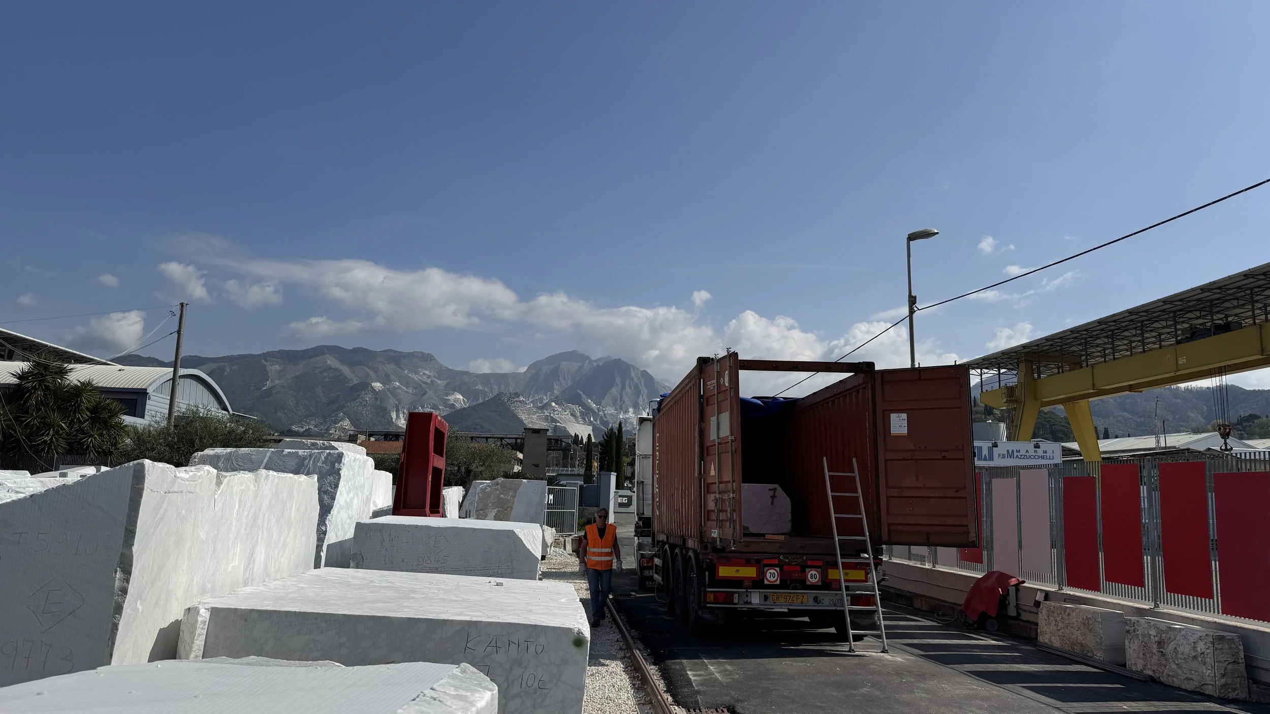 Transport yard with white marble blocks and a truck loaded for shipping.
