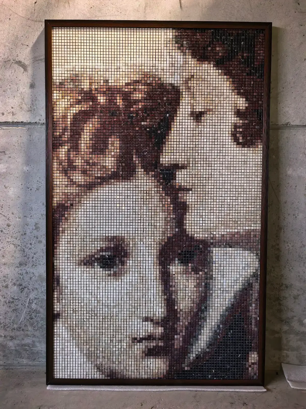Portrait mosaic artwork assembled from natural stone tesserae, shown framed before installation