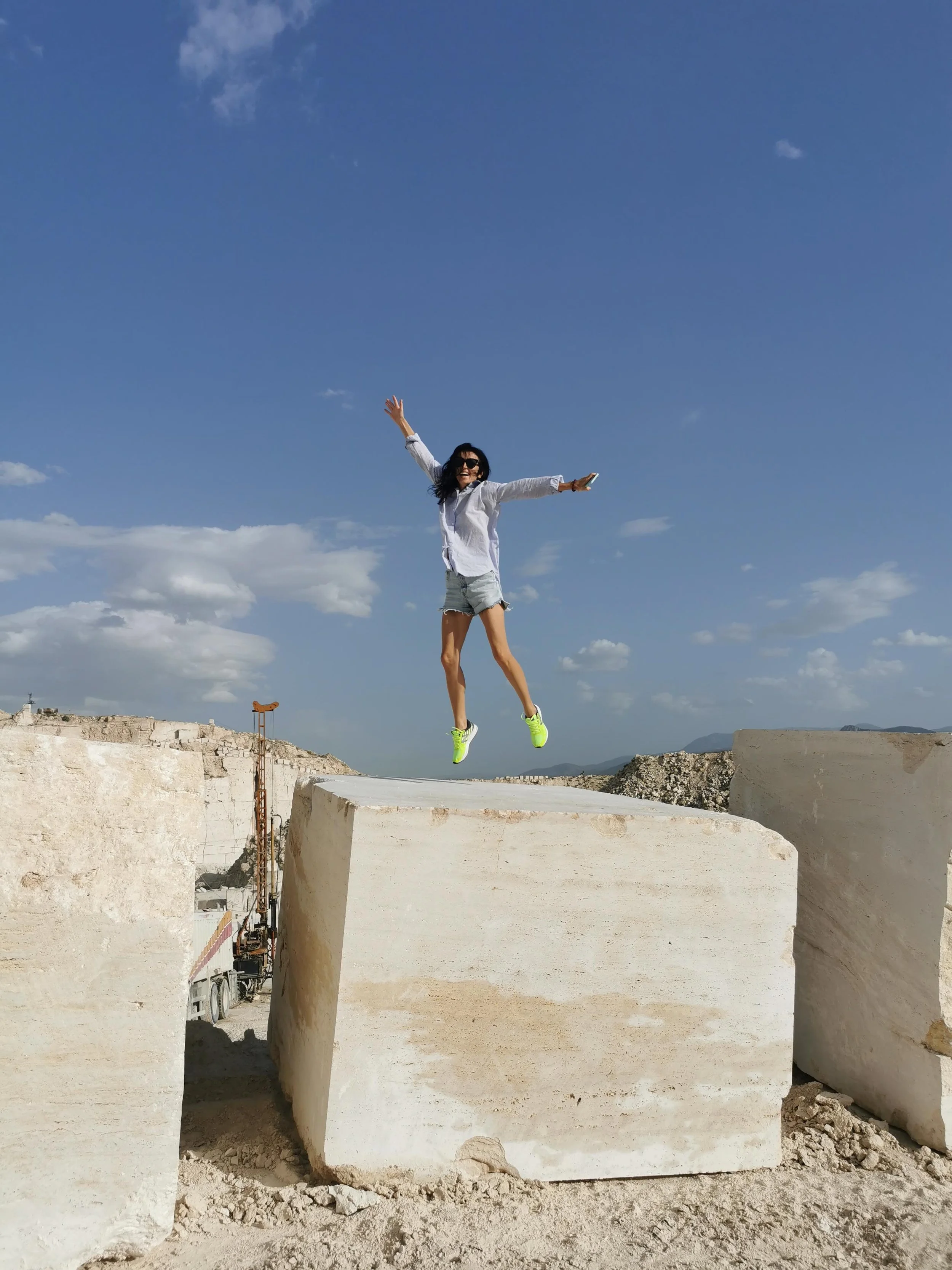Person standing atop stacked marble blocks at a G STONE quarry site.