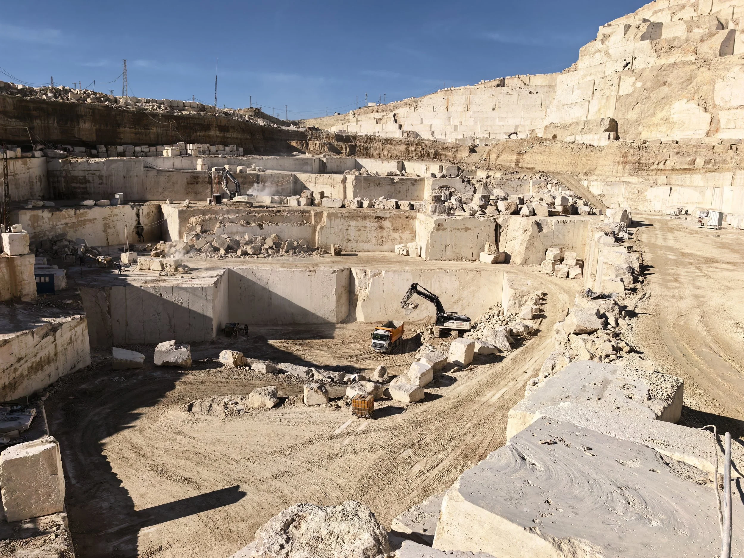 Excavation site with large cut stone blocks and heavy machinery.
