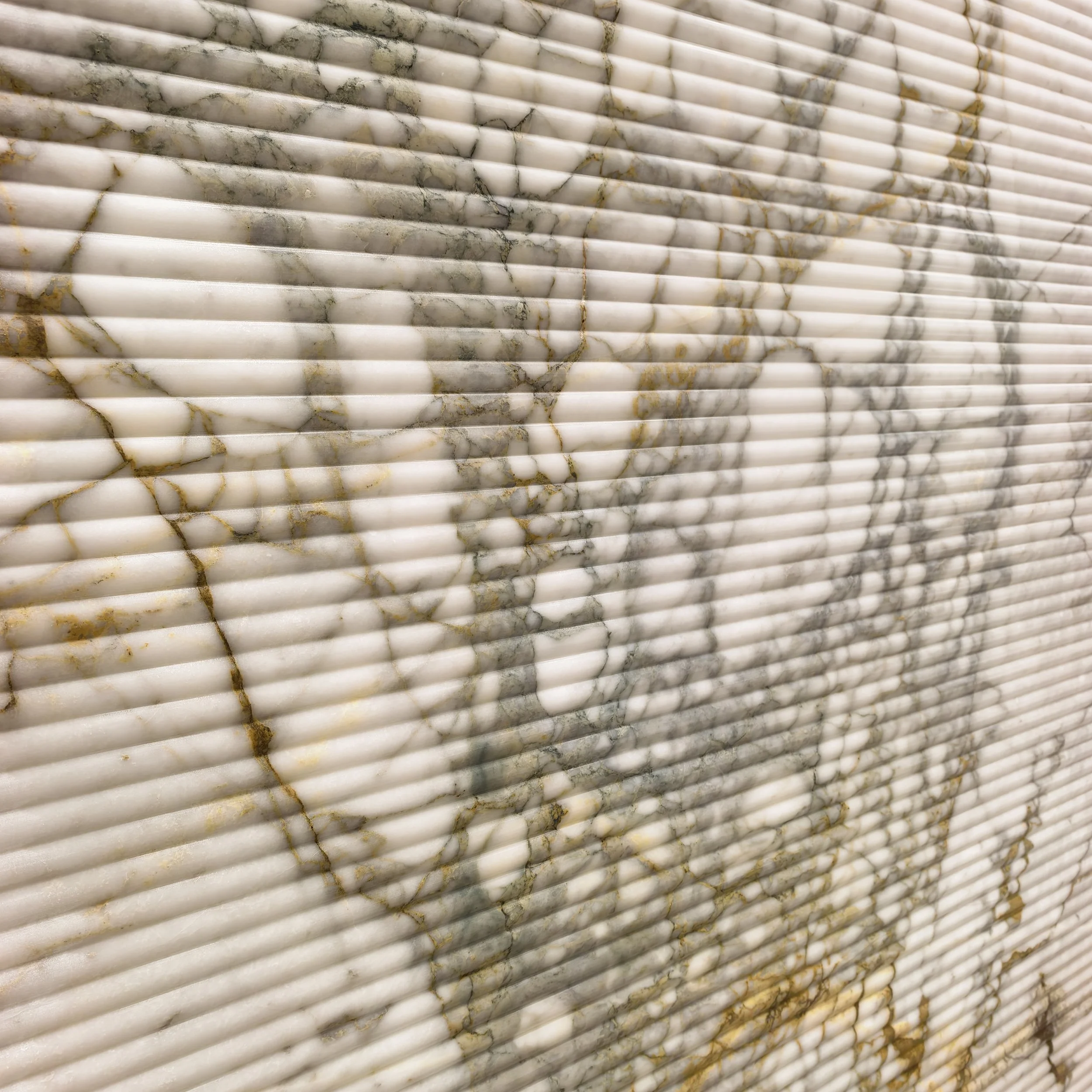 Close-up of fluted marble with white, gray and gold veining.