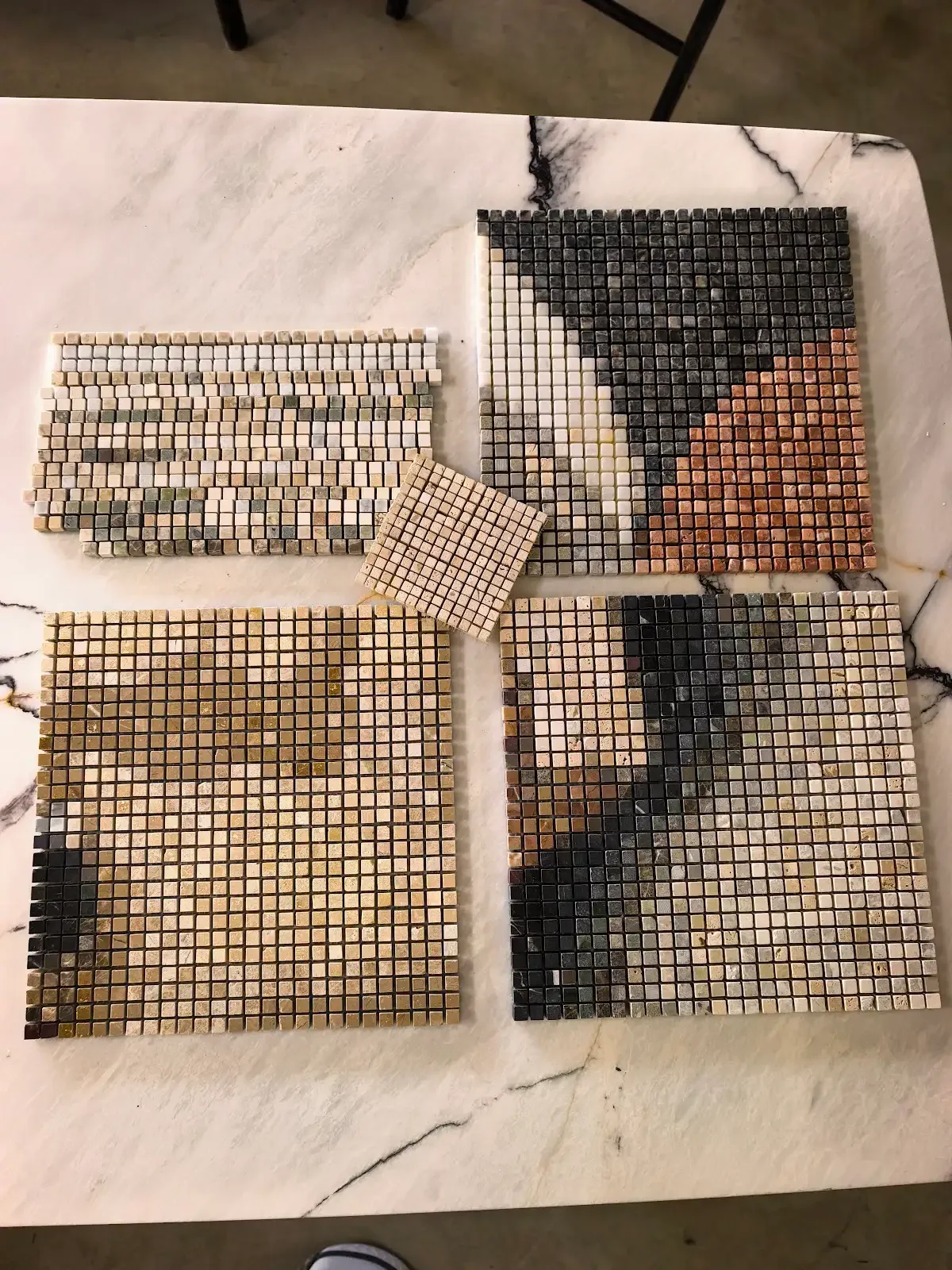 Natural stone and marble mosaic samples laid on a white marble table for palette and colour selection