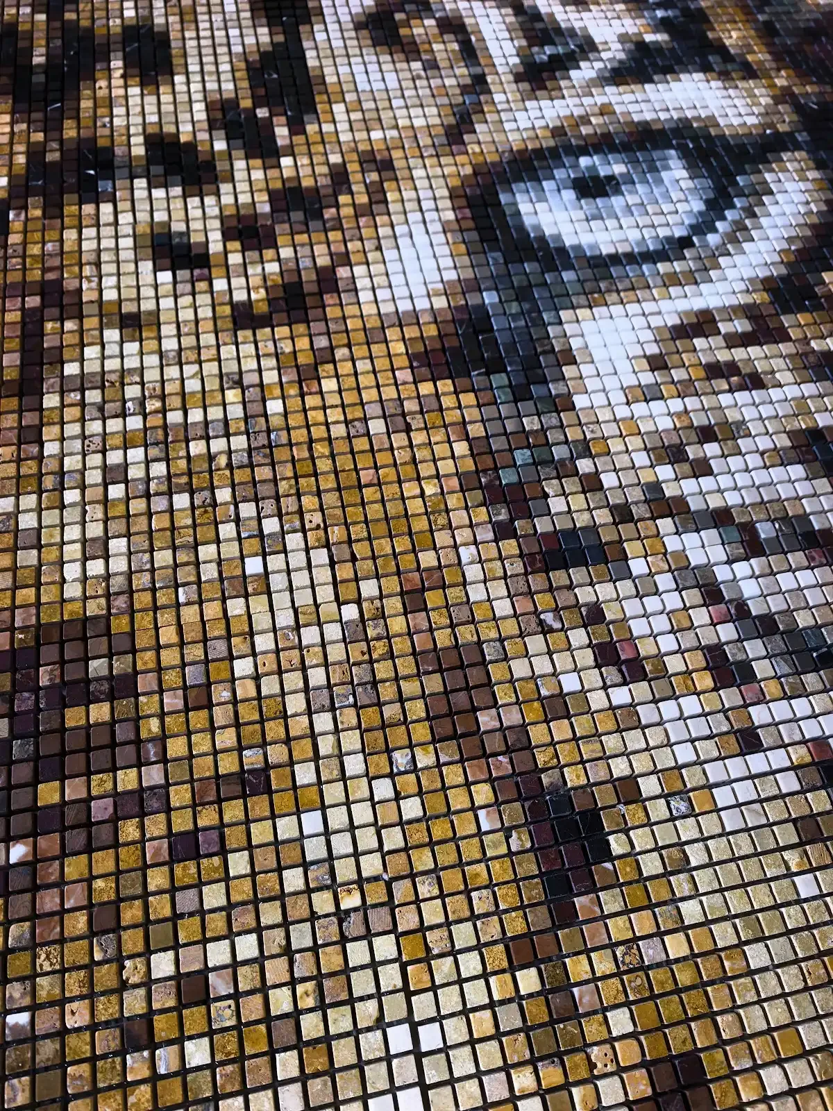 Close-up of a leopard's eye in natural stone mosaic, showing the individual stone tesserae