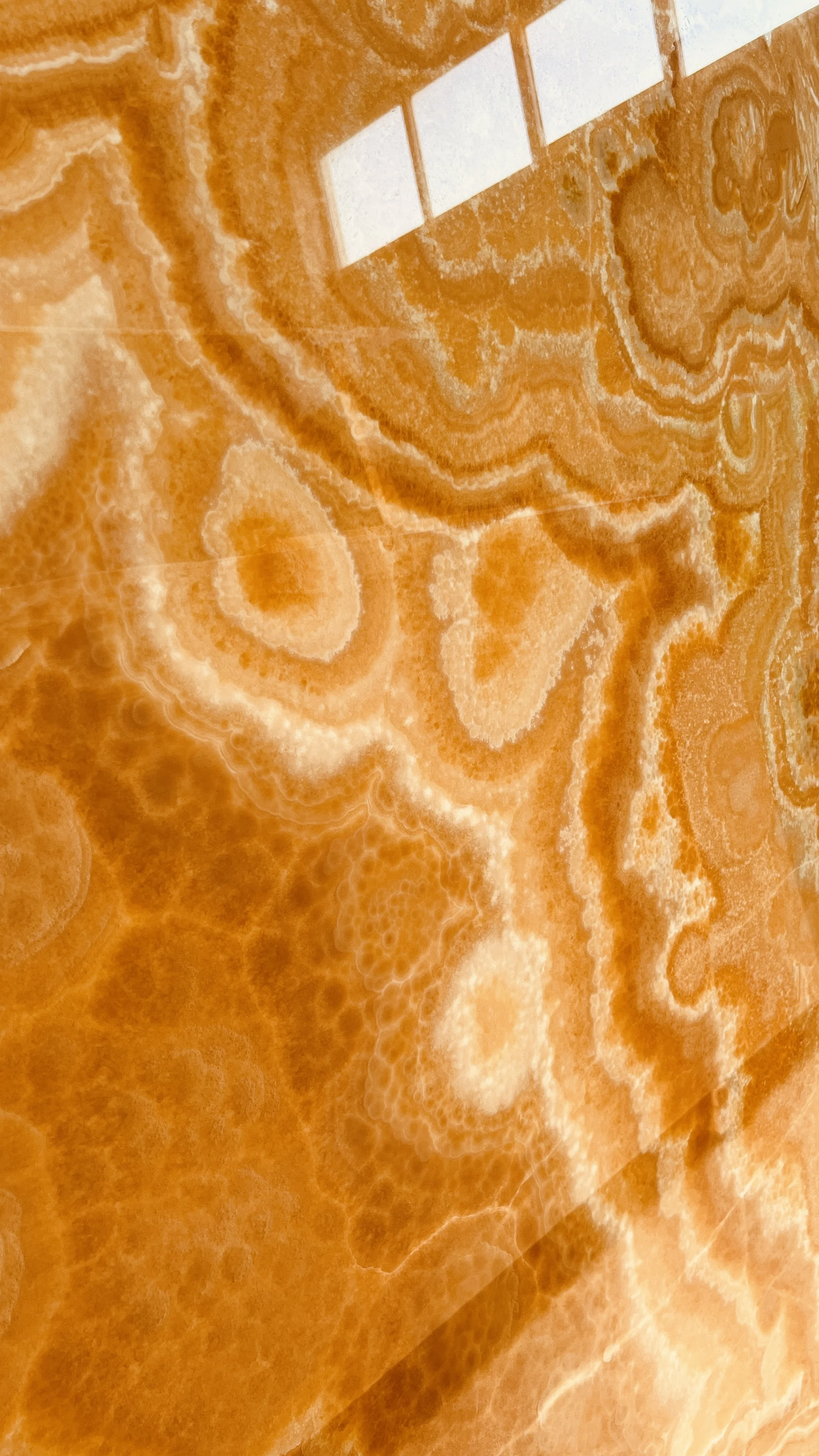 Close-up of polished orange onyx with translucent swirling veining.