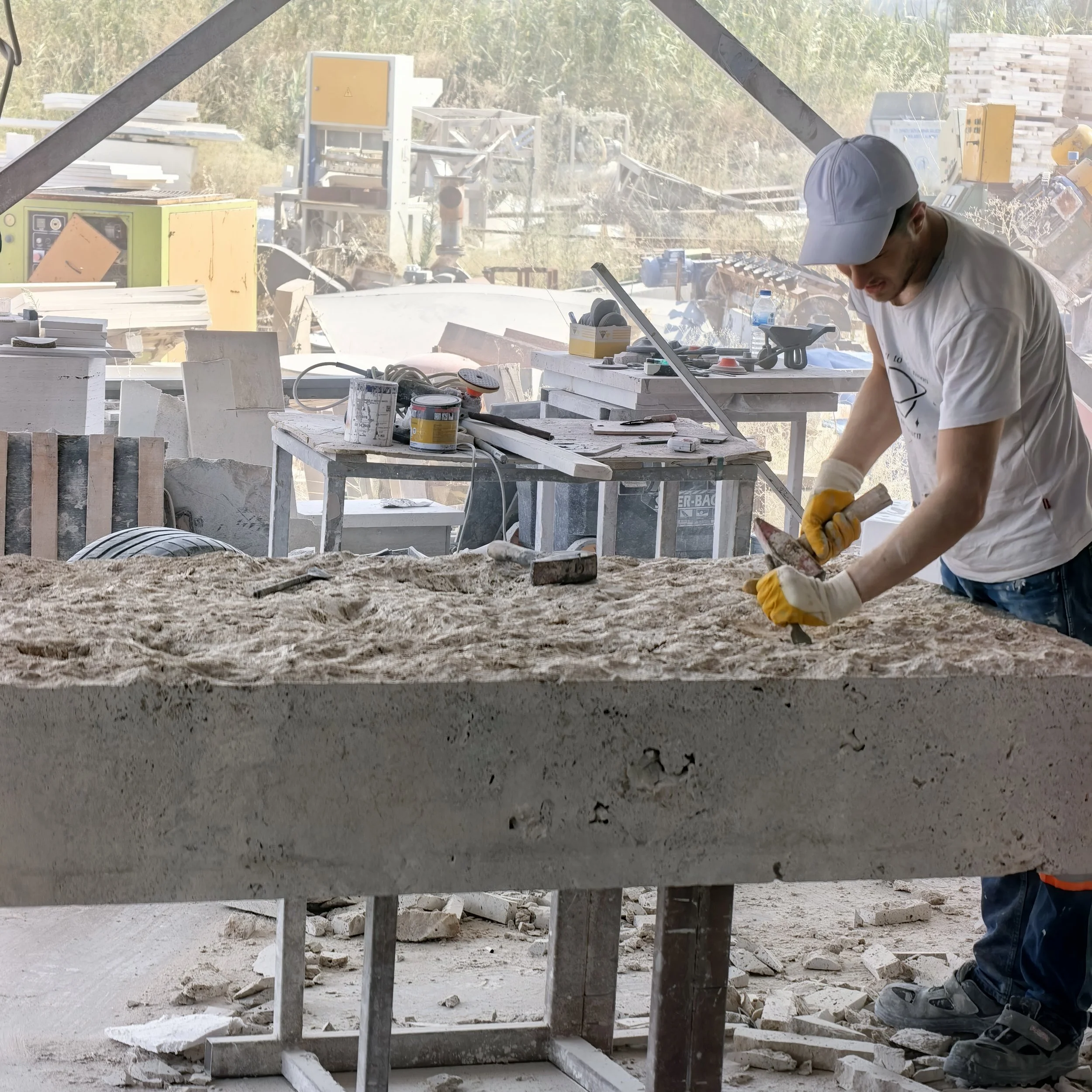 Construction worker in gloves finishing a stone slab on site.