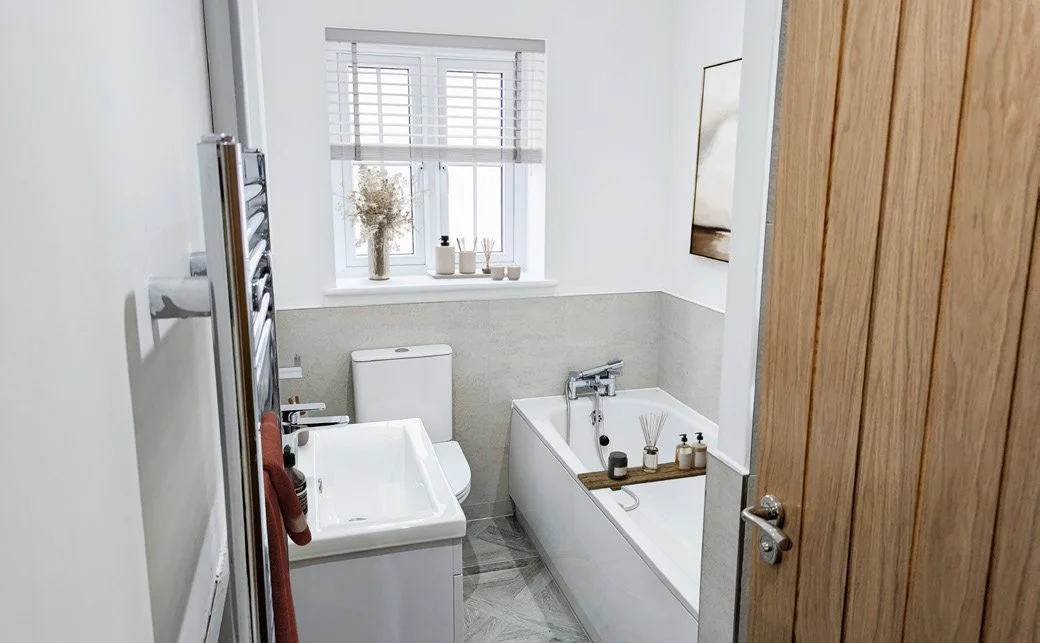 Bathroom with bathtub, toilet, and window, decorated with plants and minimal accessories.