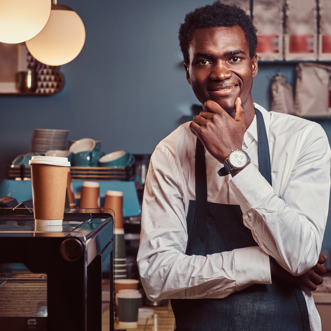 Small business owner standing behind the counter of a welcoming neighbourhood café.