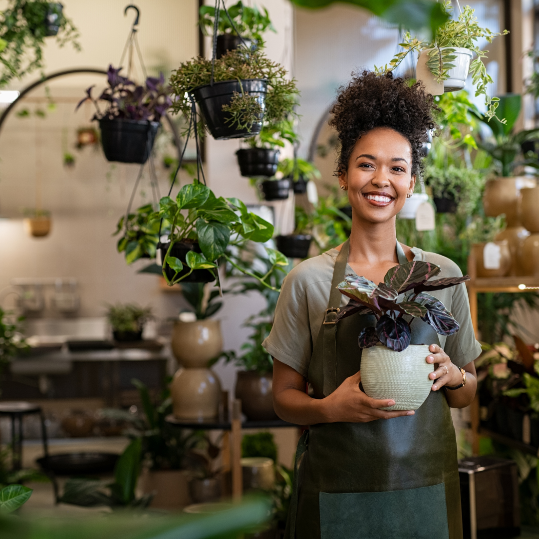 Florist holding a potted plant inside a local flower shop.