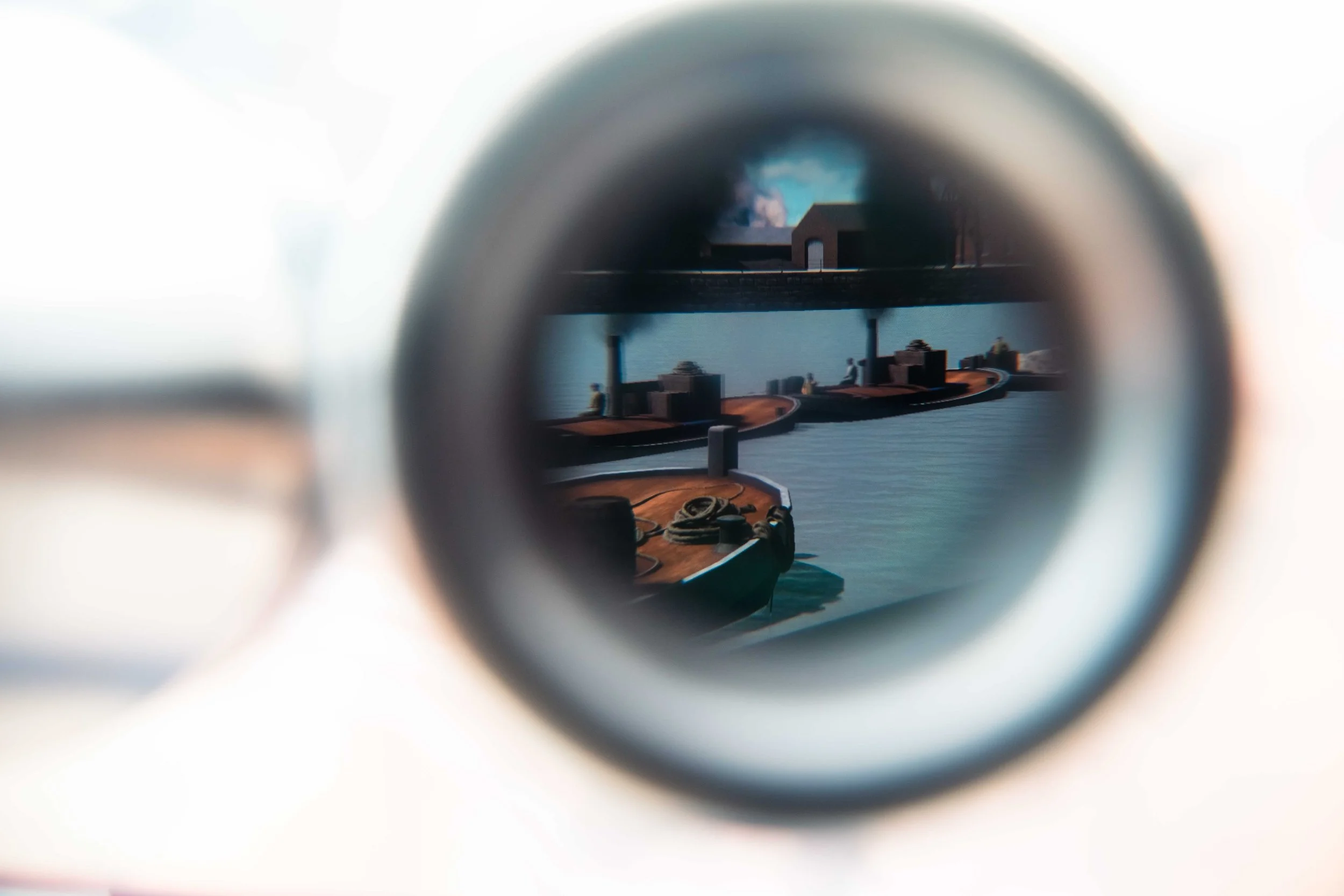 View through the scope of a telescope showing boats on a dock and a building in the background on a body of water.