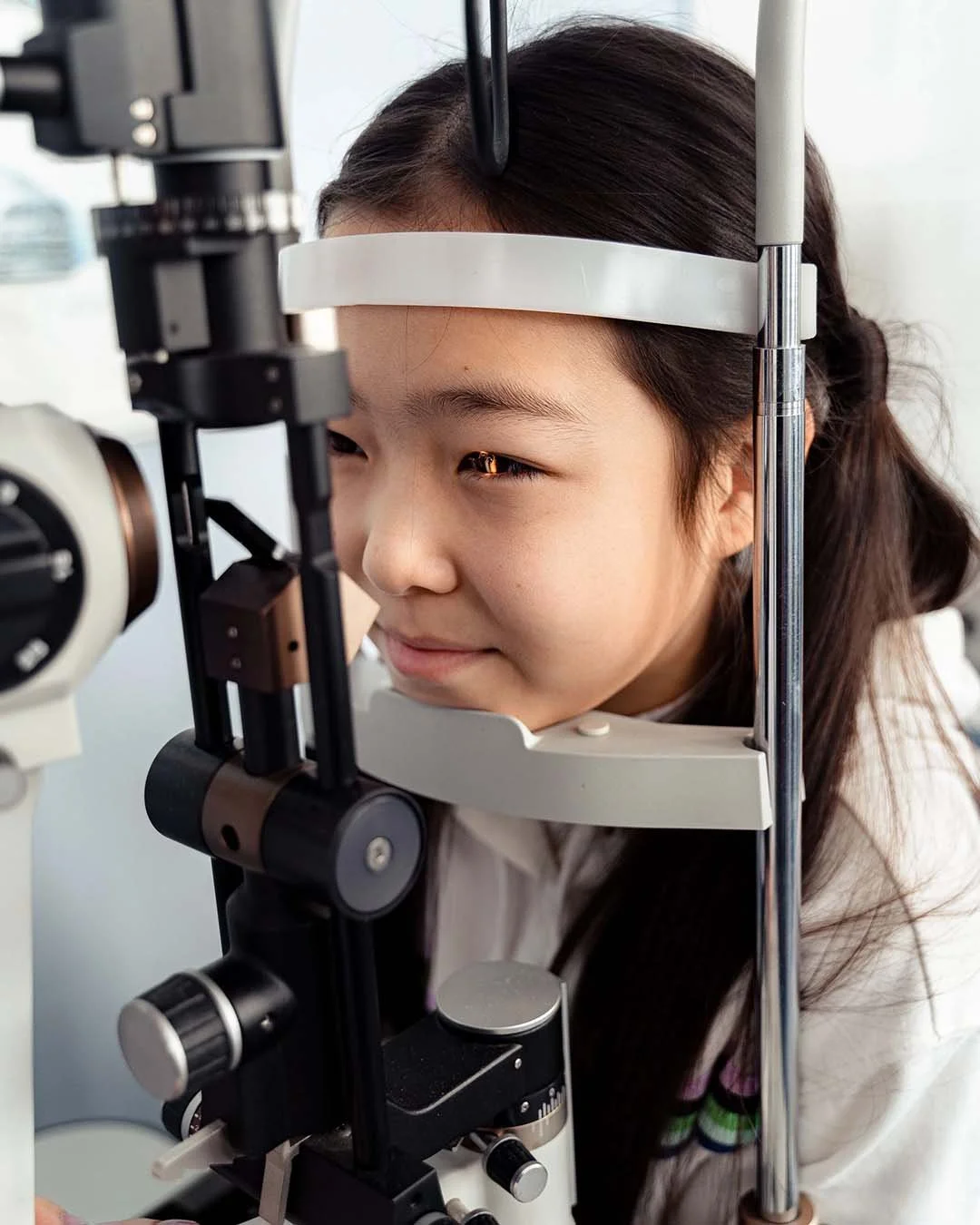 Young girl using a slit lamp at an eye exam.