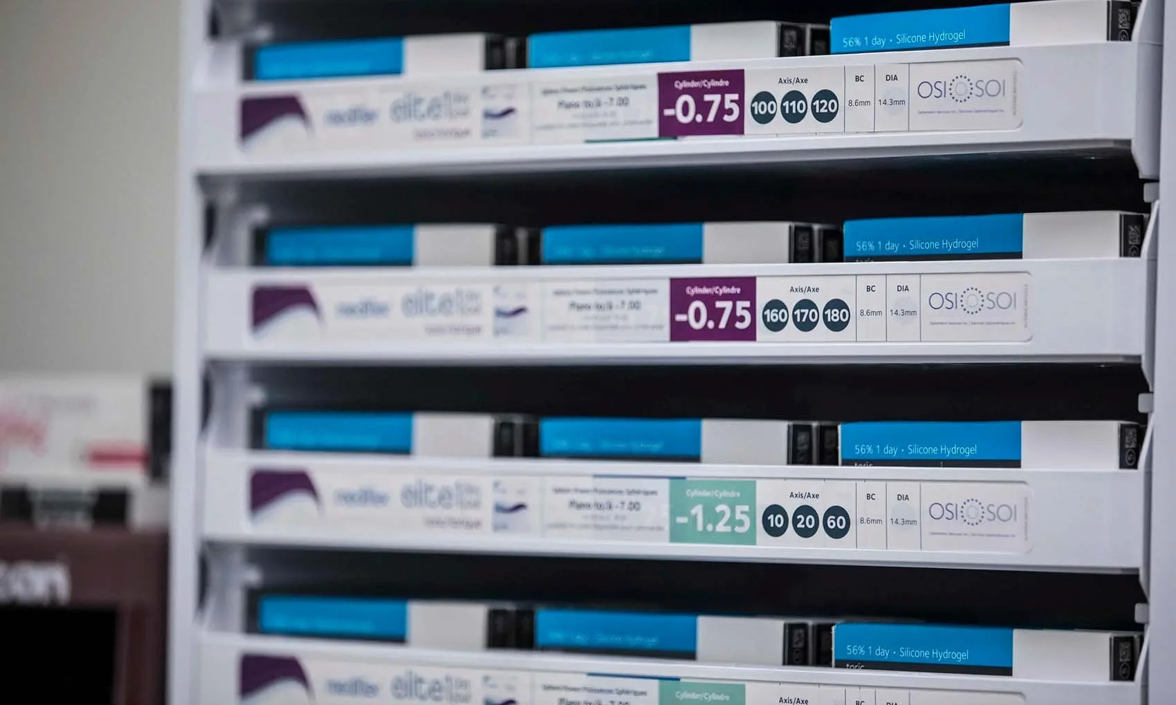 Shelves of contact lenses packaging in a store, with various prescriptions and specifications visible.