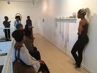 Lungiswa Gqunta vertelt een groep leerlingen over haar kunstwerk met benzinebommen, iQhiya, 2016