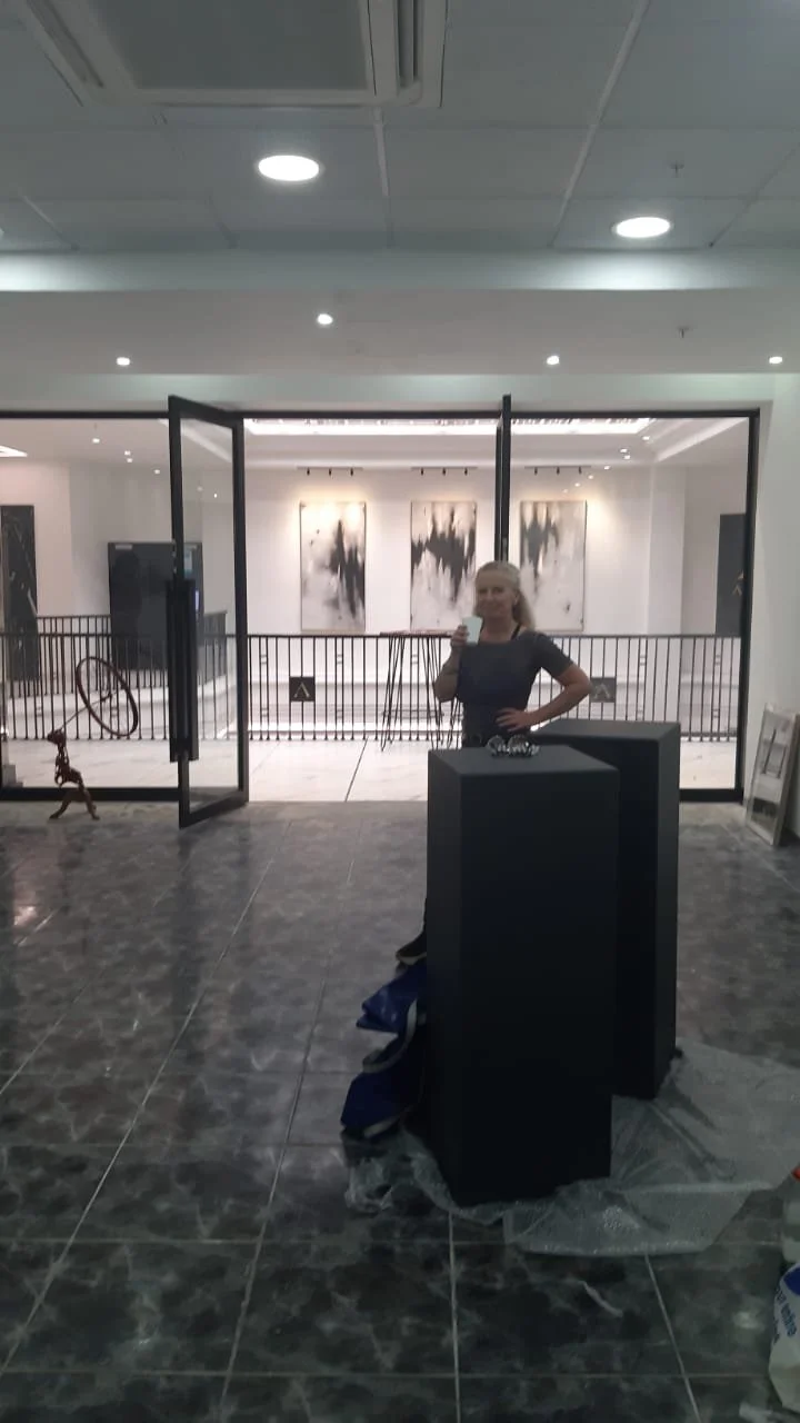 Een vrouw die in een kunstgalerie selfies neemt met haar smartphone, terwijl ze rechtop staat en poseert.