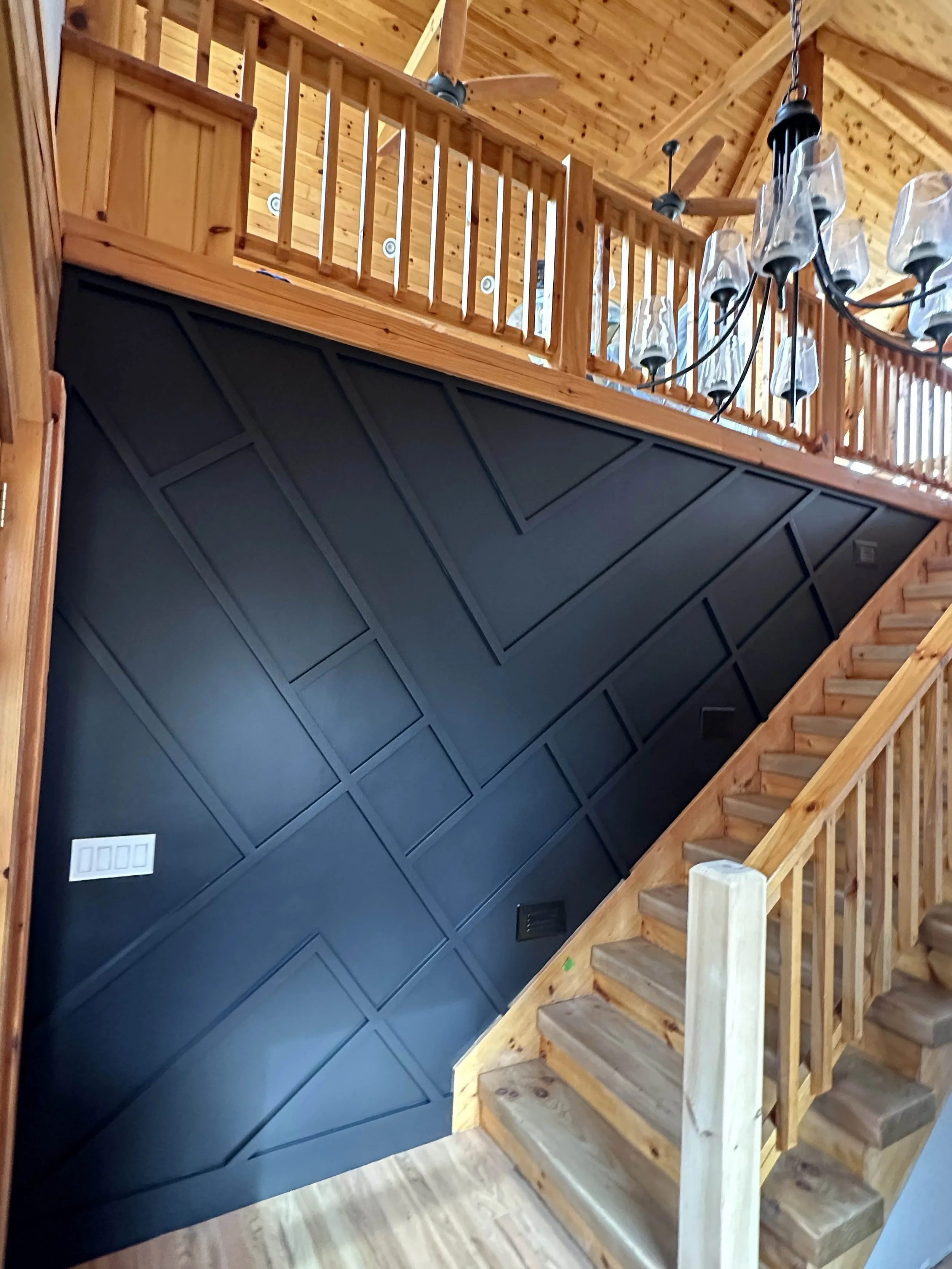Interior renovation with custom black wainscoting accent wall and wood staircase