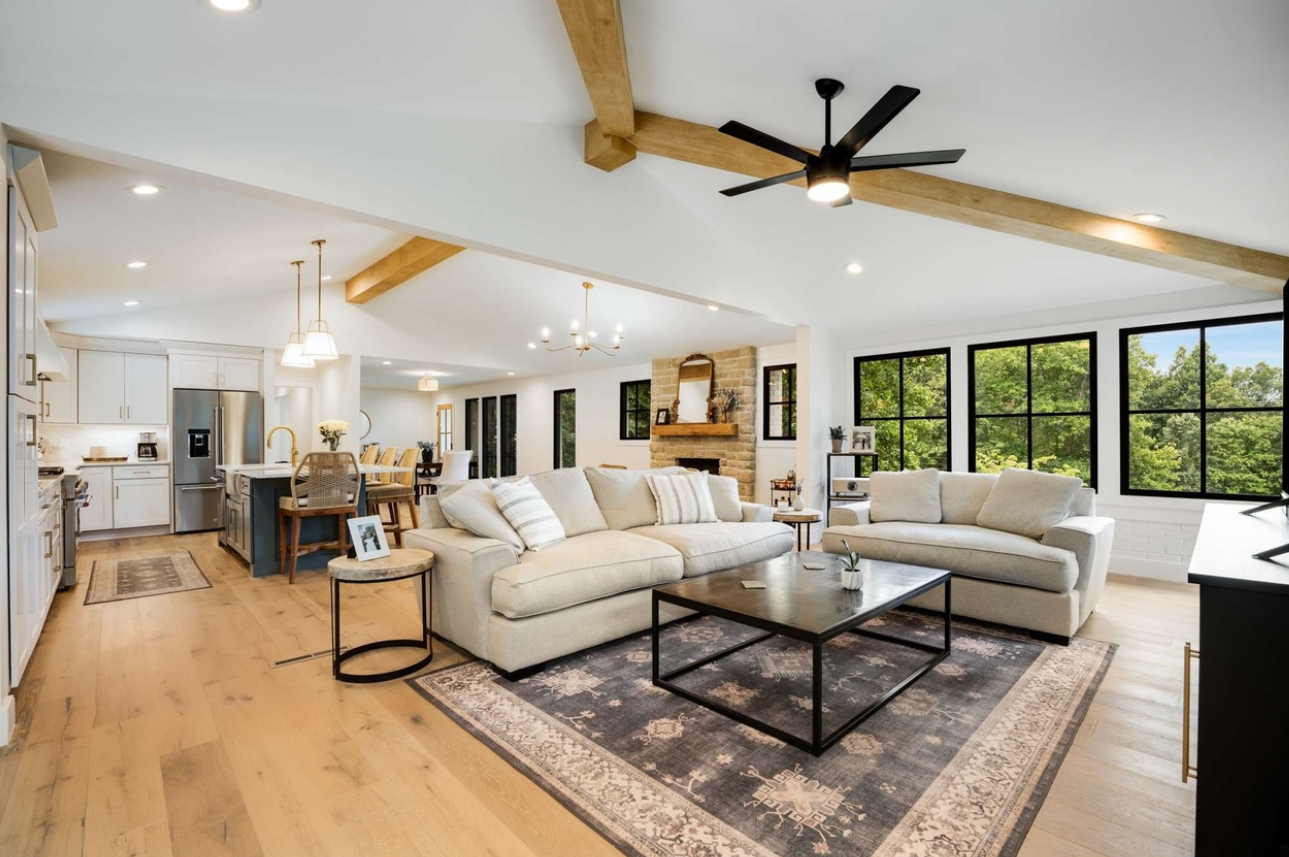 Open-concept home renovation with custom kitchen, living room and exposed wood beams, hardwood flooring, window replacement