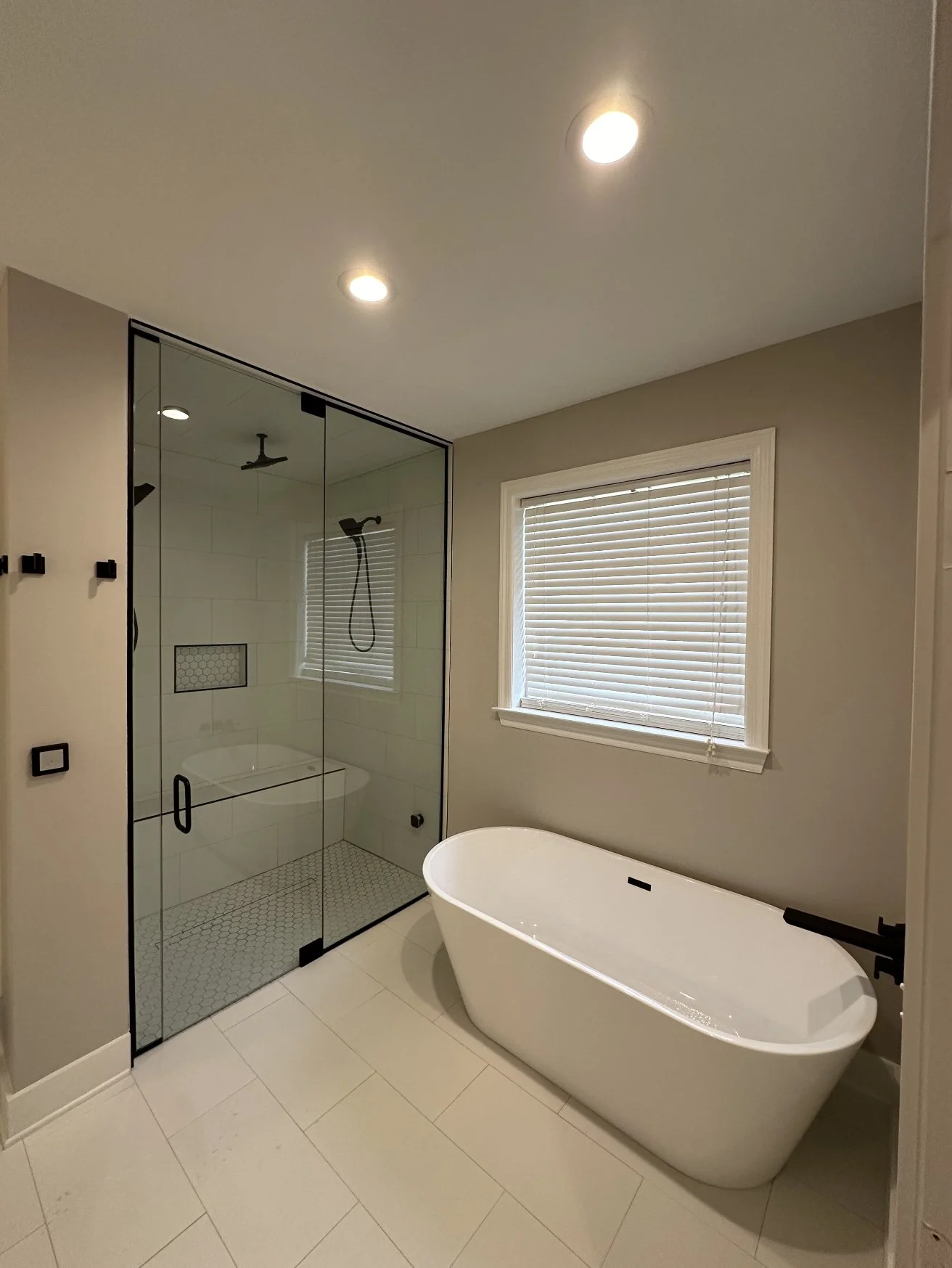Primary bathroom renovation with freestanding tub, black-framed walk-in steam shower, glass door