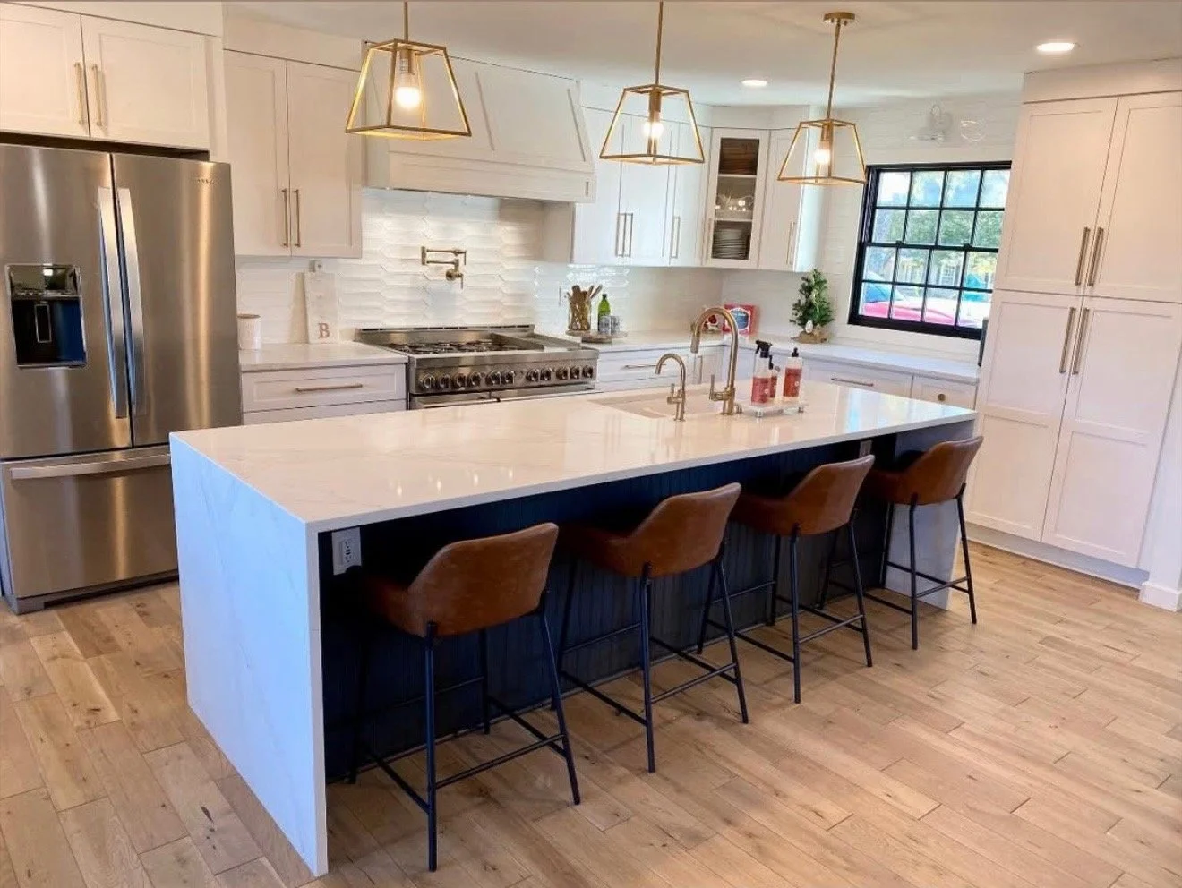 Remodeled kitchen with large waterfall island, white cabinetry and hardwood floors