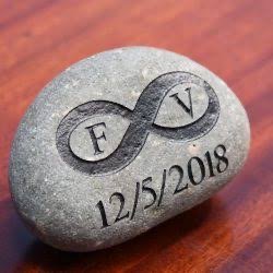 A gray commemorative stone with an engraved infinity symbol containing the initials 'F' and 'V', and the date '12/5/2018' beneath it.