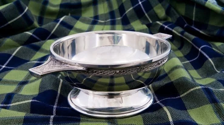 Silver serving dish with a lid, placed on a green and blue plaid fabric.