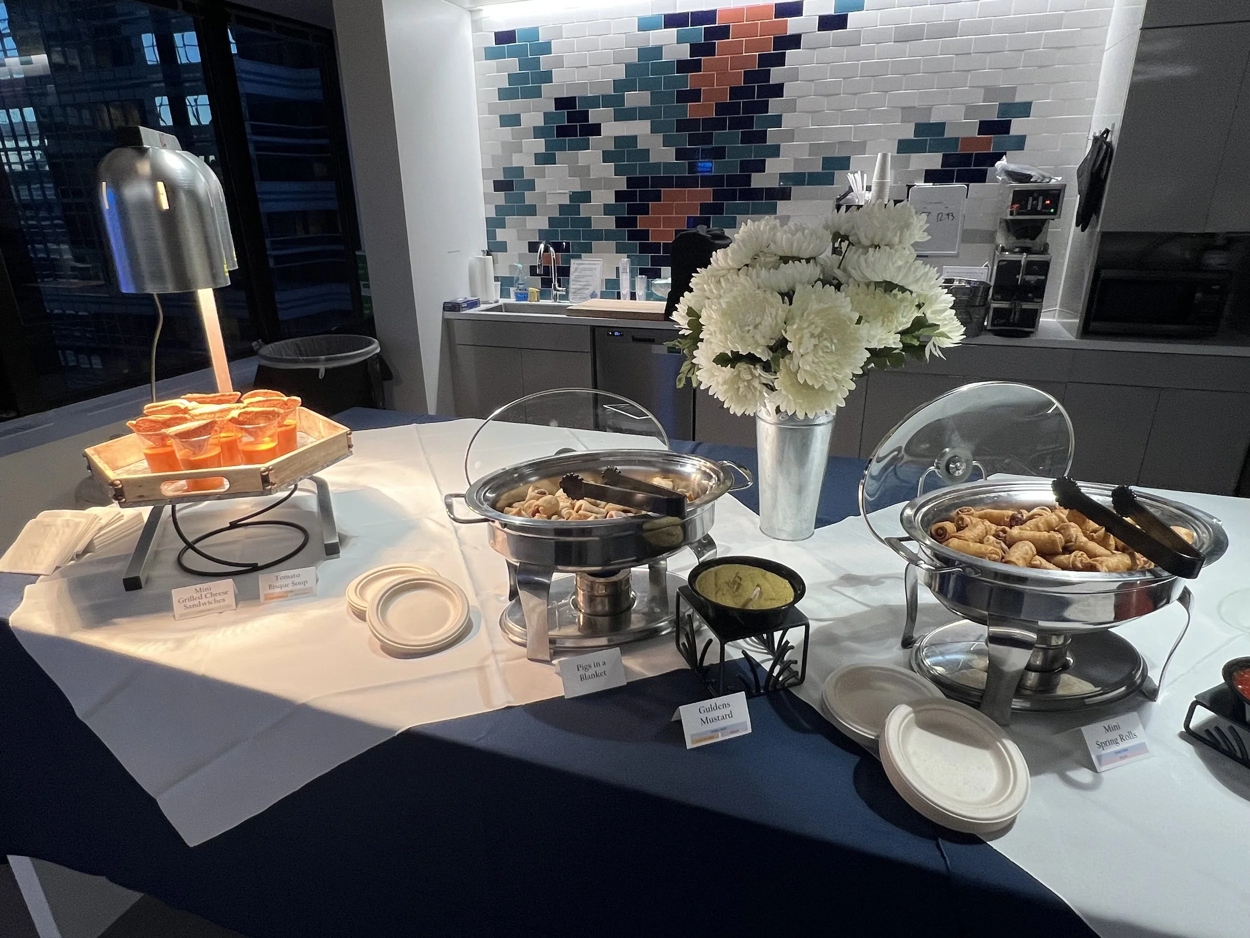 Corporate event buffet table with catered dishes and floral arrangements in a Philadelphia corporate office