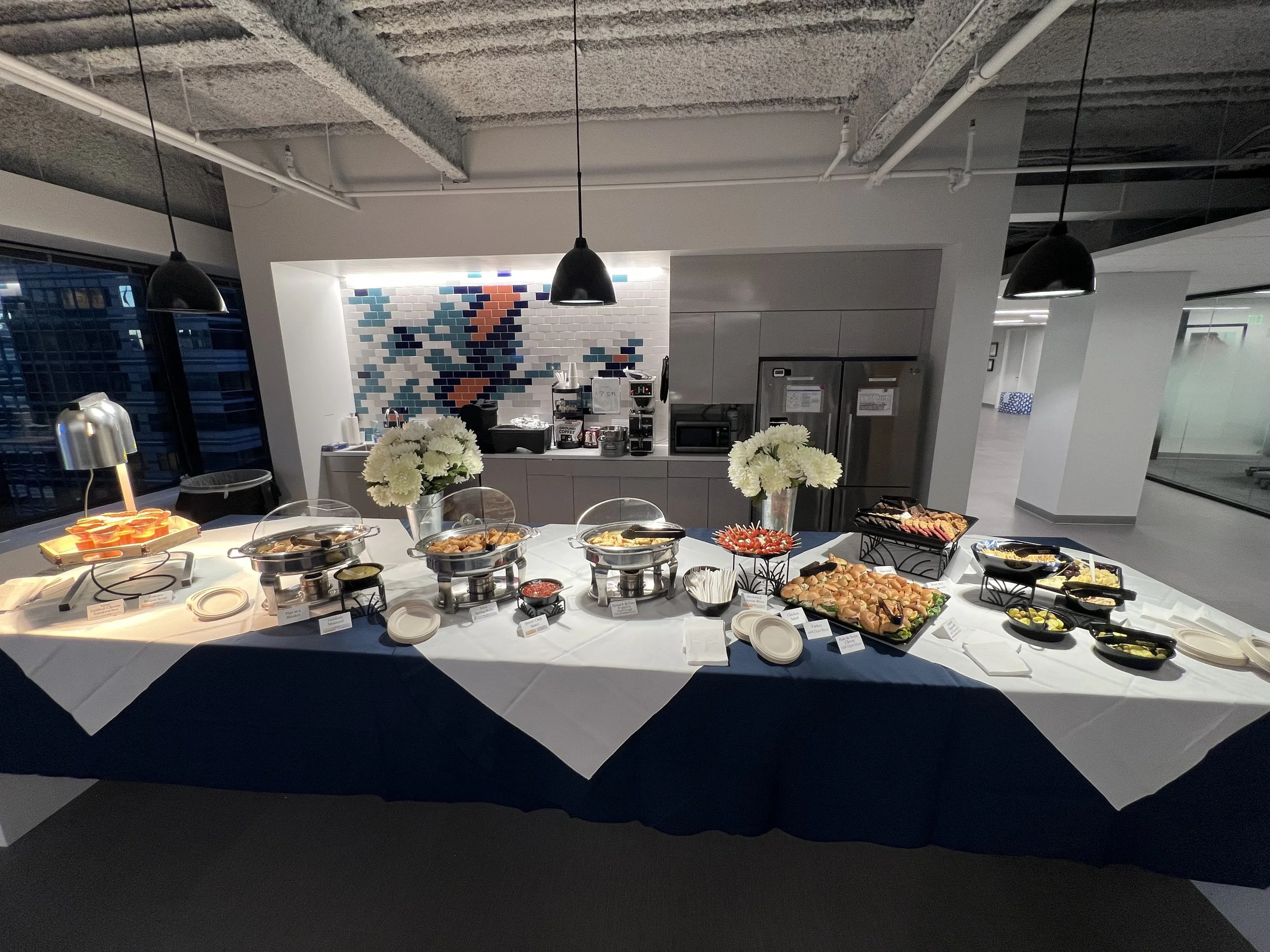 Corporate event buffet table with catered dishes and floral arrangements in a Philadelphia corporate office
