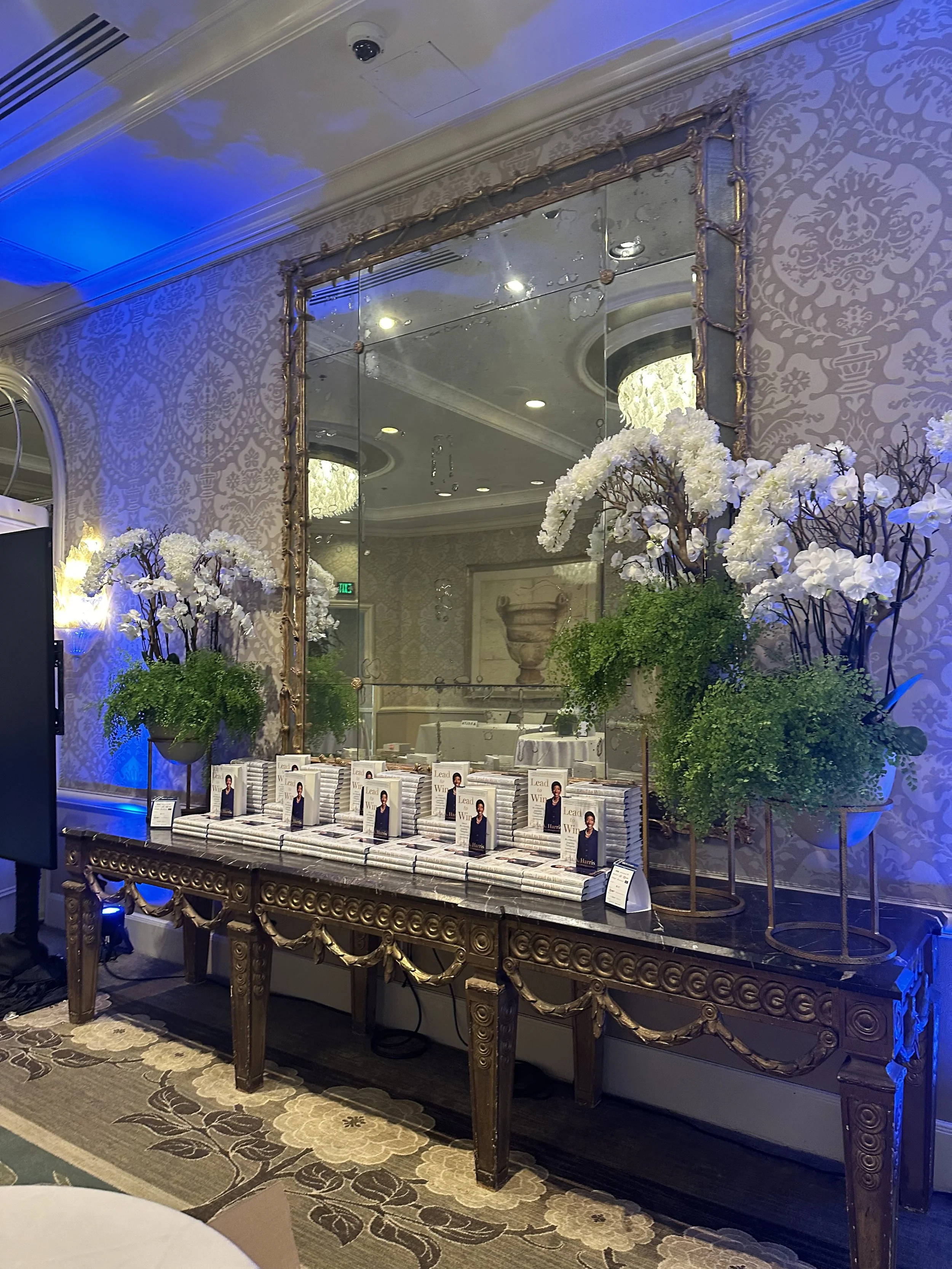 A decorated table displays copies of a book titled 'Lead to Win' for a book launch event