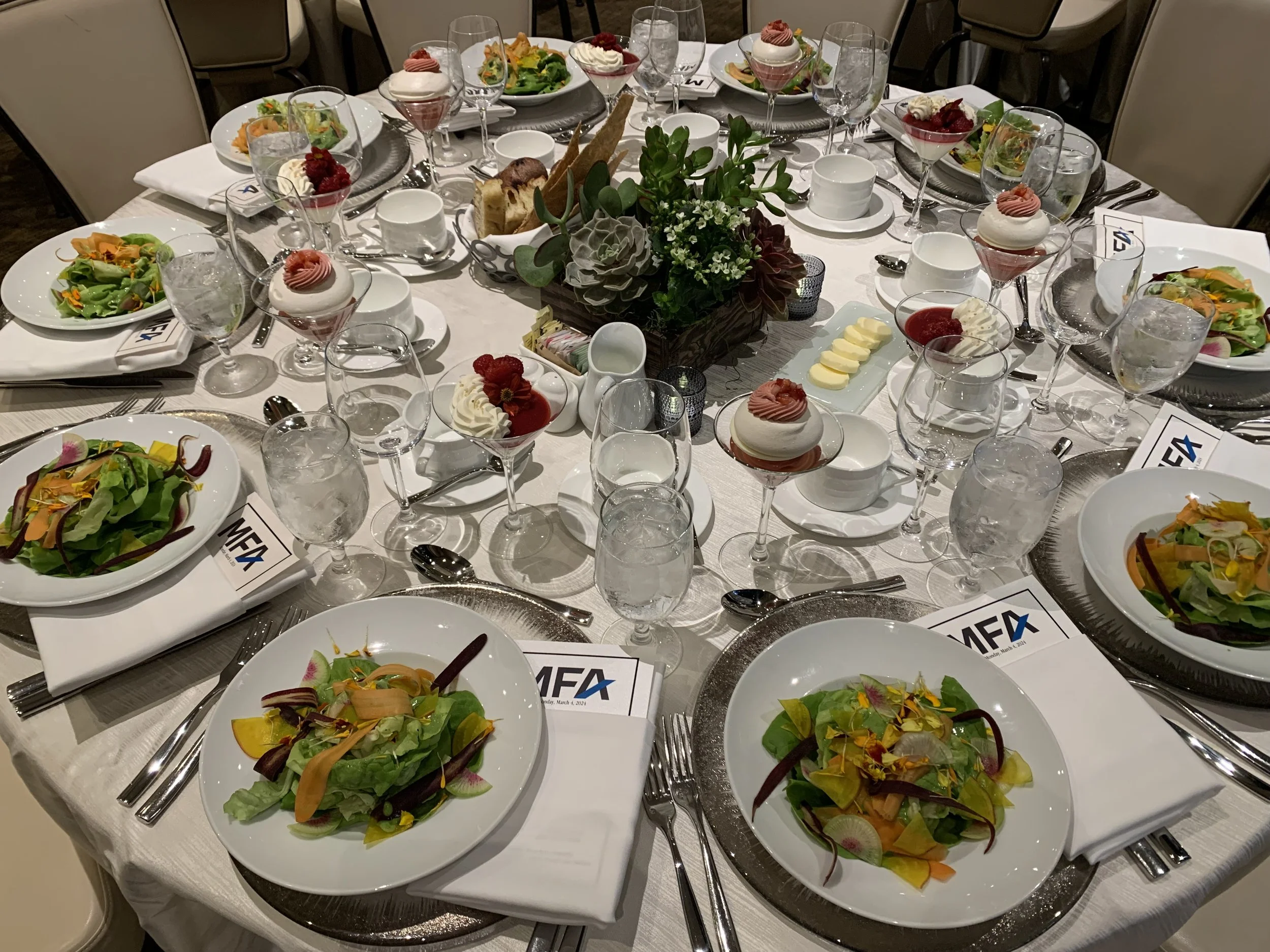 VIP corporate board of directors dinner table setting with formal place settings and elegant floral centerpiece