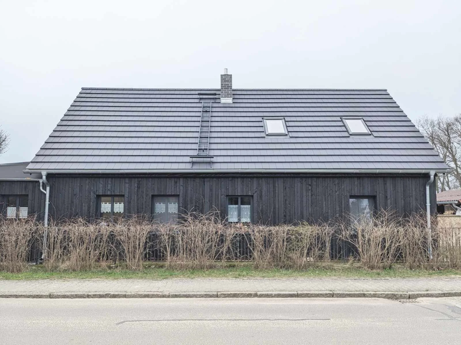 Fassade aus gebranntem Holz und neuem Schieferdach von Haus B im Spreewald, geplant von d'ns Studio