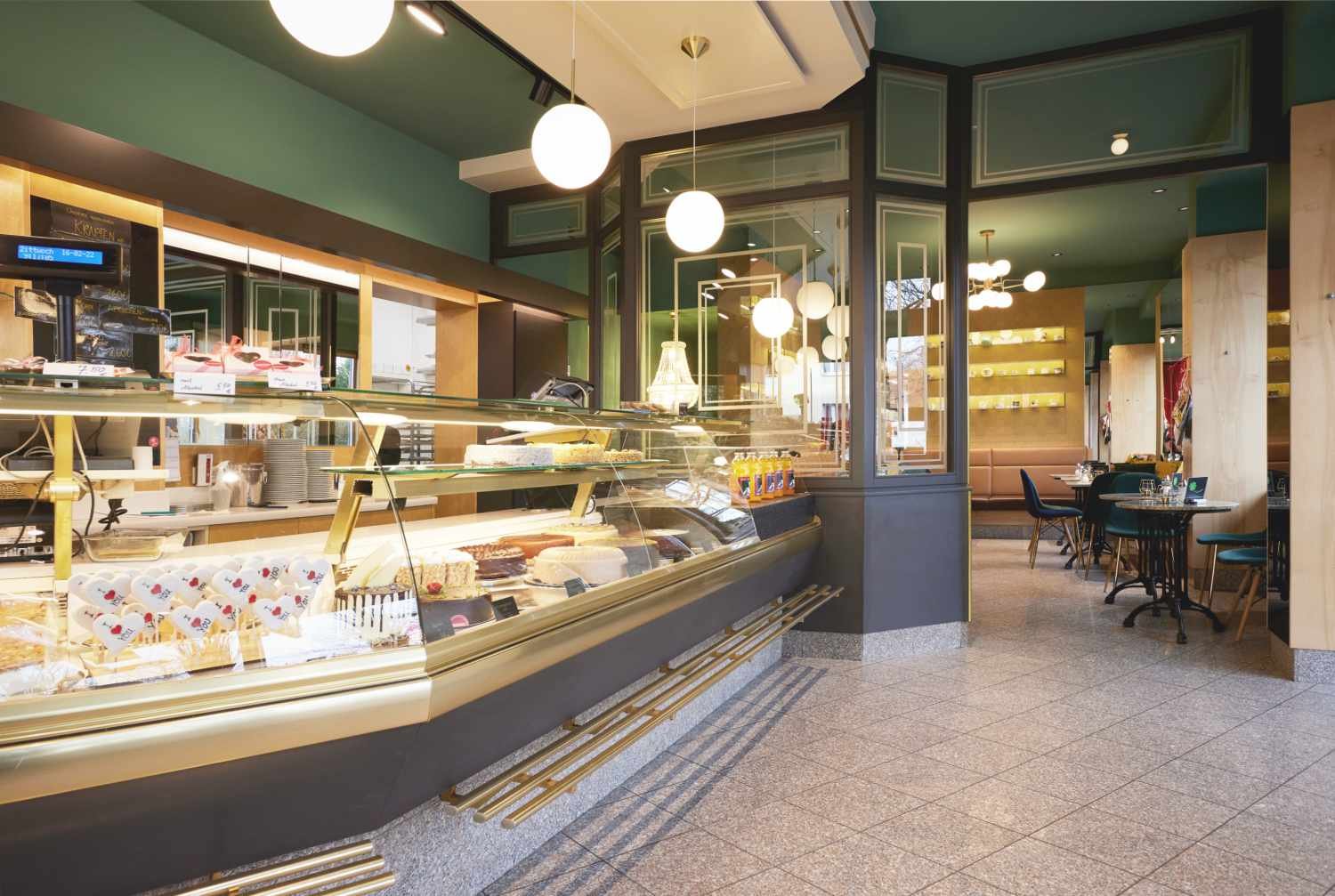 Verkaufsraum mit grünem Decken- und Wandanstrich und neuer Beleuchtung in der Konditorei Detterbeck in München, geplant von d'ns Studio
