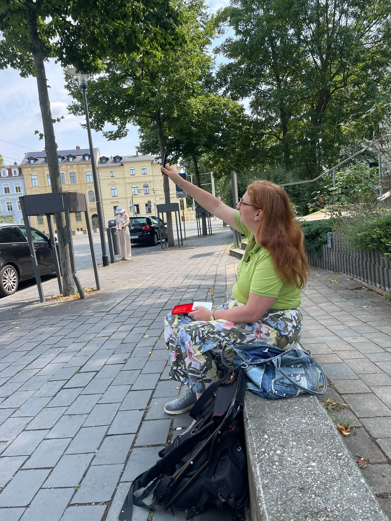 Ivonne Wenzel beim Urban Sketching in Gera. Auf einer kleinen mauer sitzend vermisst sie den Dachwinkel eines Gebäudes für ihre Skizze. Urban Sketching verbindet Beobachtung, Zeichnen und das unmittelbare Erleben eines Ortes.